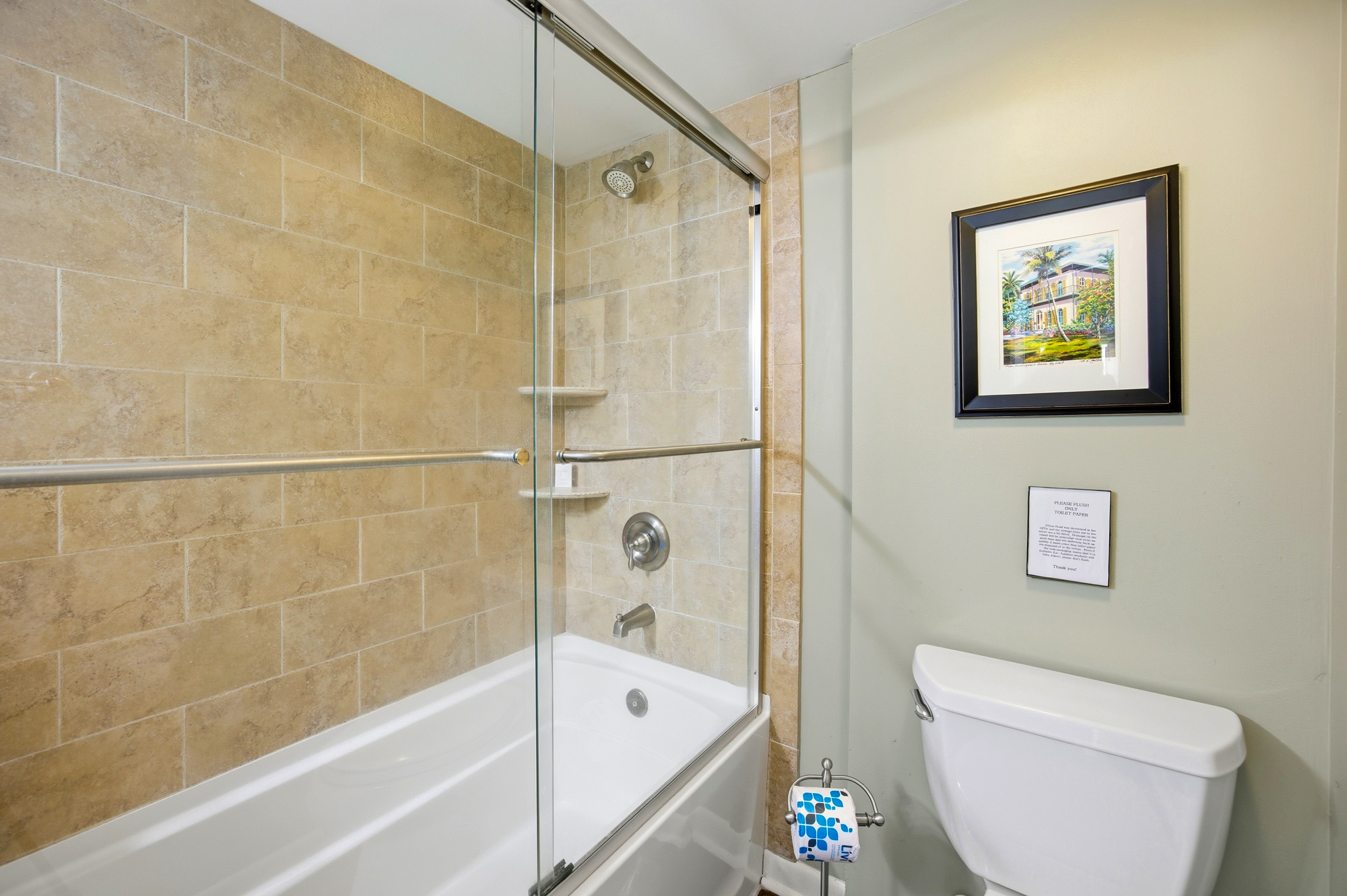 Warm earth tones glow across the textured tile walls, creating a calm backdrop for a long soak in the deep tub. Clear glass doors and bright white finishes keep this tidy bathroom feeling open and airy.