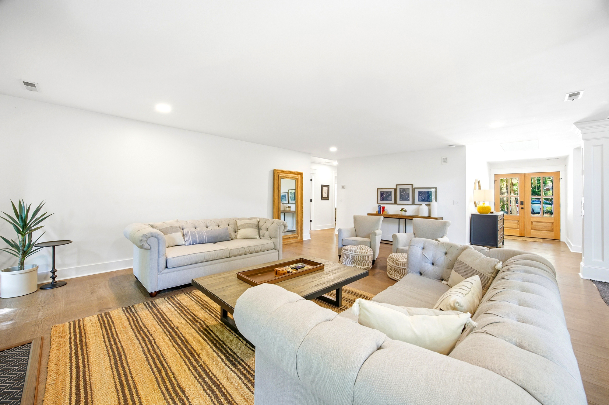 Tufted linen sofas and a textured jute rug anchor this airy living space, where soft daylight spills across rich oak floors. Reclaimed wood accents and clean lines create a grounding atmosphere perfect for lingering conversations.