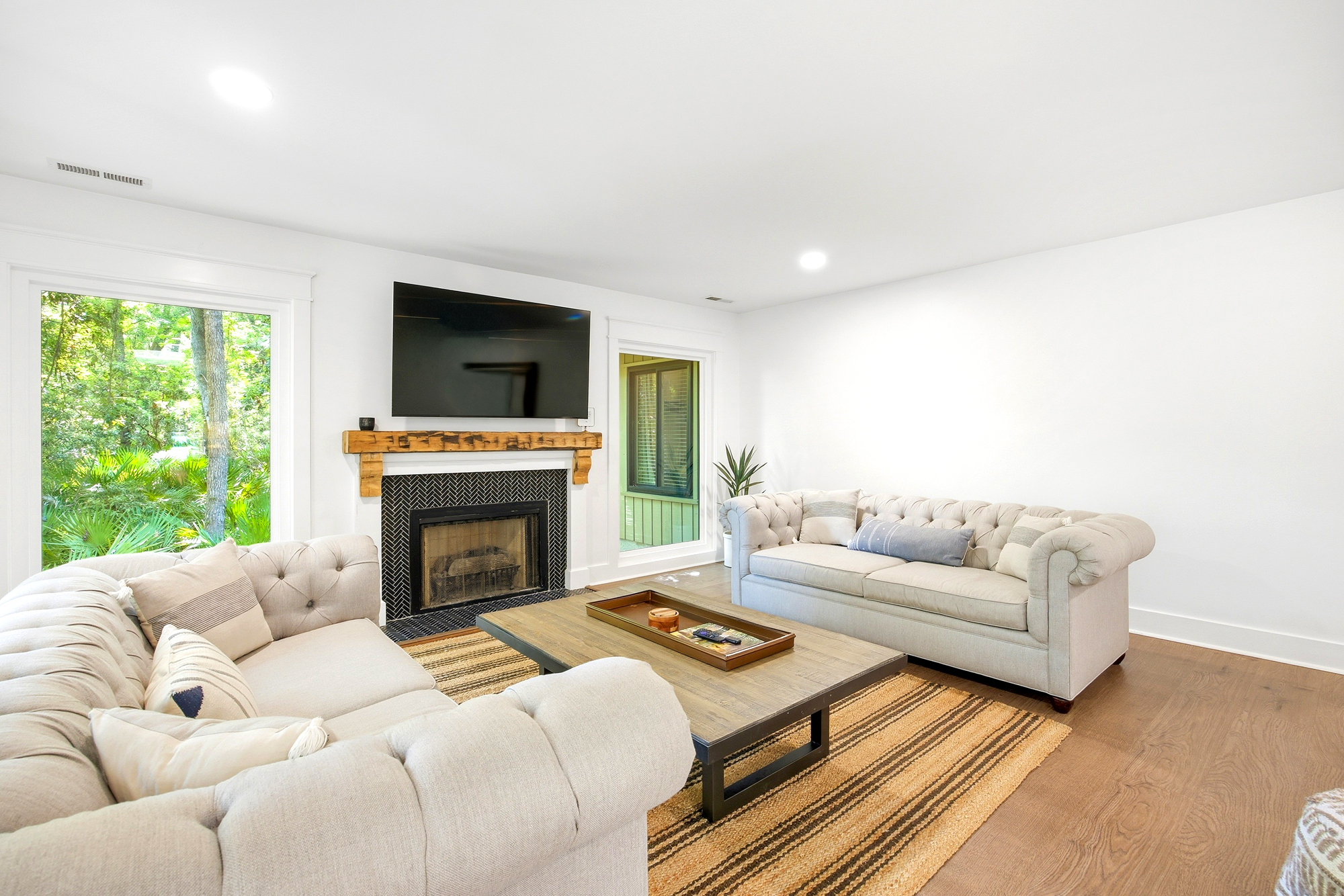 Textured linens and a rustic mantel anchor this airy living room, where forest views peek through large windows. Sink into the deep sofas for a quiet evening by the tiled hearth and reclaimed wood accents.