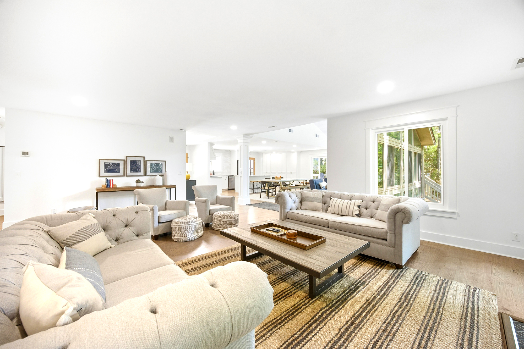 Cloudy tones and textured linens anchor this airy lounge, where daylight pours through wide windows to illuminate the open floor plan. Reclaimed wood and woven fibers create a tactile, grounded atmosphere perfect for quiet afternoon tea.