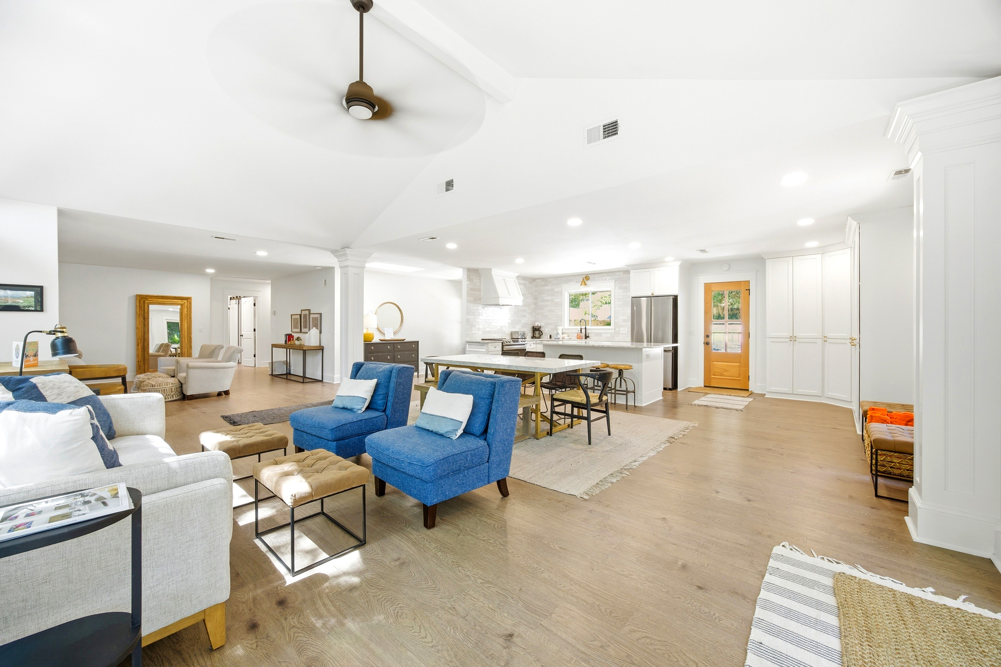 Cerulean armchairs bring a splash of coastal color to this airy open floor plan, where vaulted ceilings and honey-toned wood floors create a sense of calm. Bright surroundings and soft textures make this the perfect hub for gathered conversation.