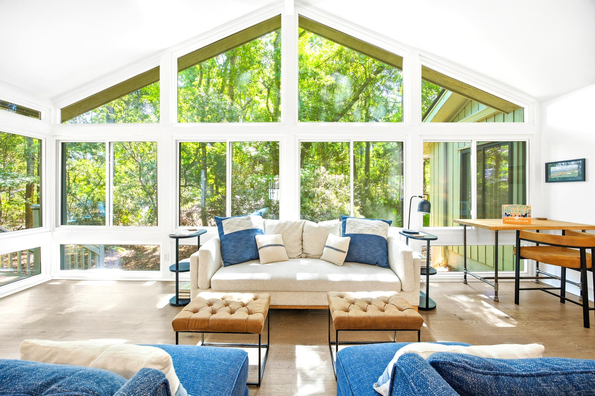 Verdant views pour through floor-to-ceiling windows, turning this airy sunroom into a bright sanctuary. Plush seating and warm leather footstools invite you to linger as afternoon glow illuminates the crisp, white cathedral ceilings.