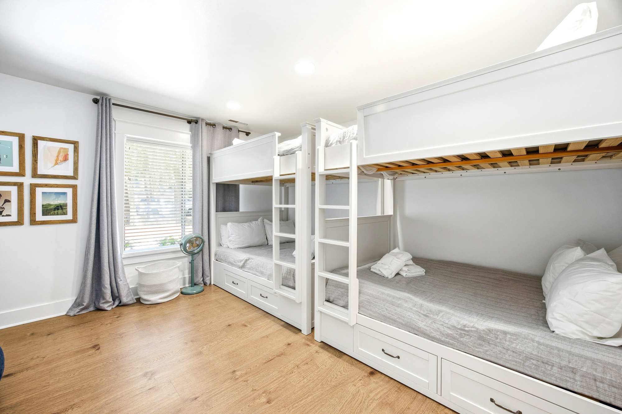 Crisp white bunk beds line this airy room, offering a cozy nook for every guest. Golden oak floors and filtered daylight create a bright, peaceful space perfect for groups to recharge after a day of adventure.
