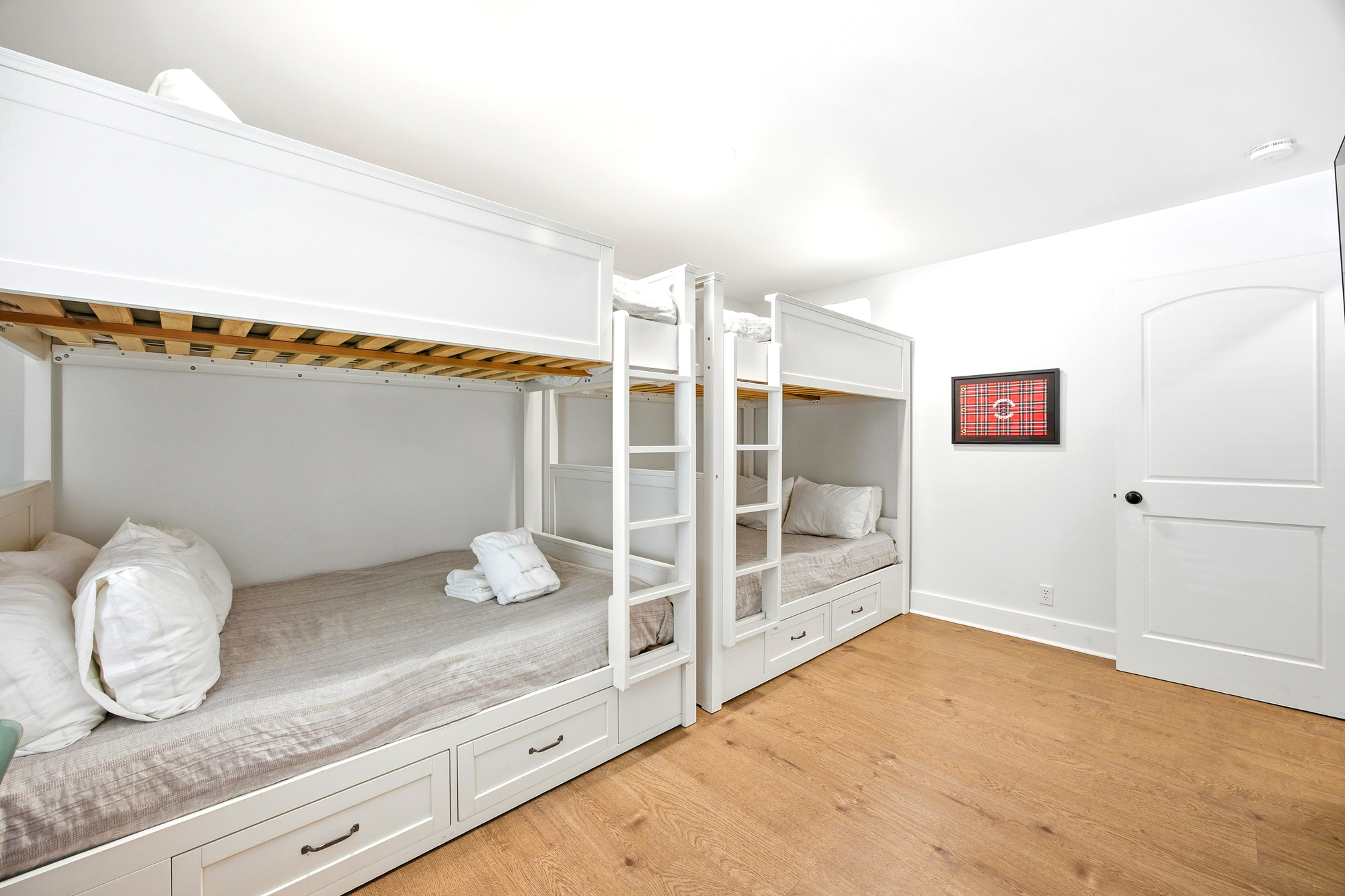 Sturdy built-in bunks offer a peaceful sleep for the whole group, featuring clean lines and clever storage drawers. Oak-toned floors and bright walls create a cheerful, open atmosphere perfect for winding down after a day of adventure.