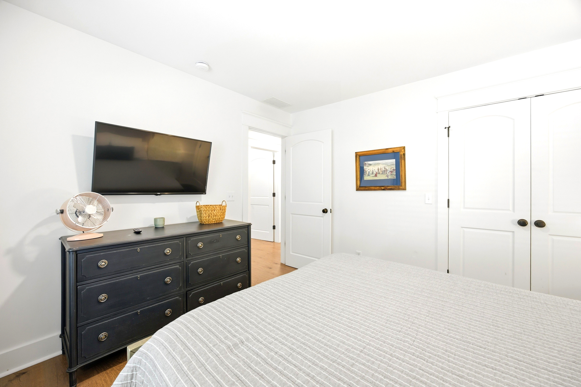 Ebony wood tones ground this airy bedroom, where clean lines and a minimalist palette create a serene atmosphere. Settle into the striped linens and catch your favorite show as afternoon brightness fills every corner of this calm sanctuary.