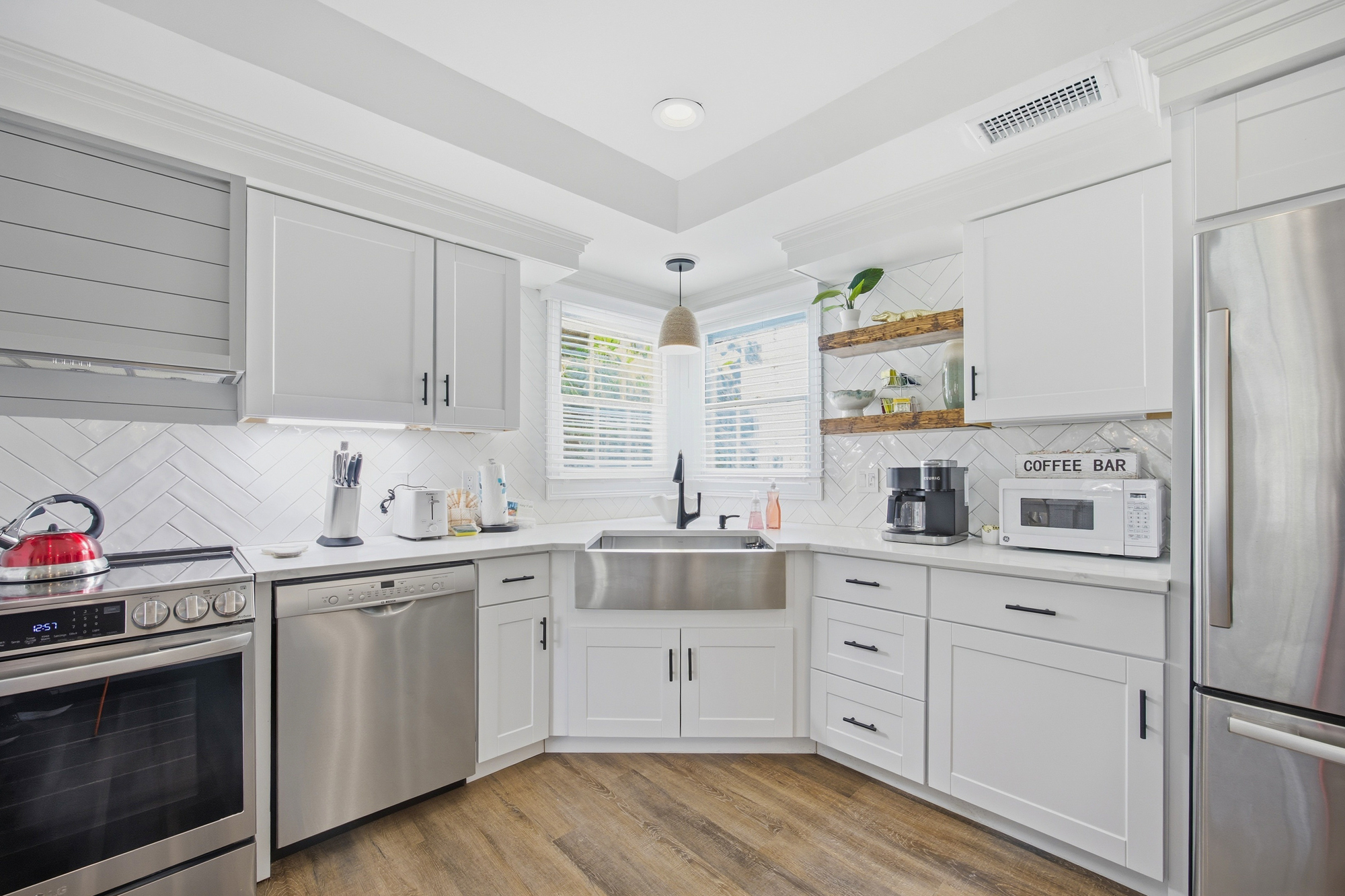 Honeycomb tiles and warm wood shelving create a bright, texture-rich corner for your morning brew. Shimmering stainless steel and snow-hued cabinetry offer a clean, airy space to prepare local treats in the gentle daylight.