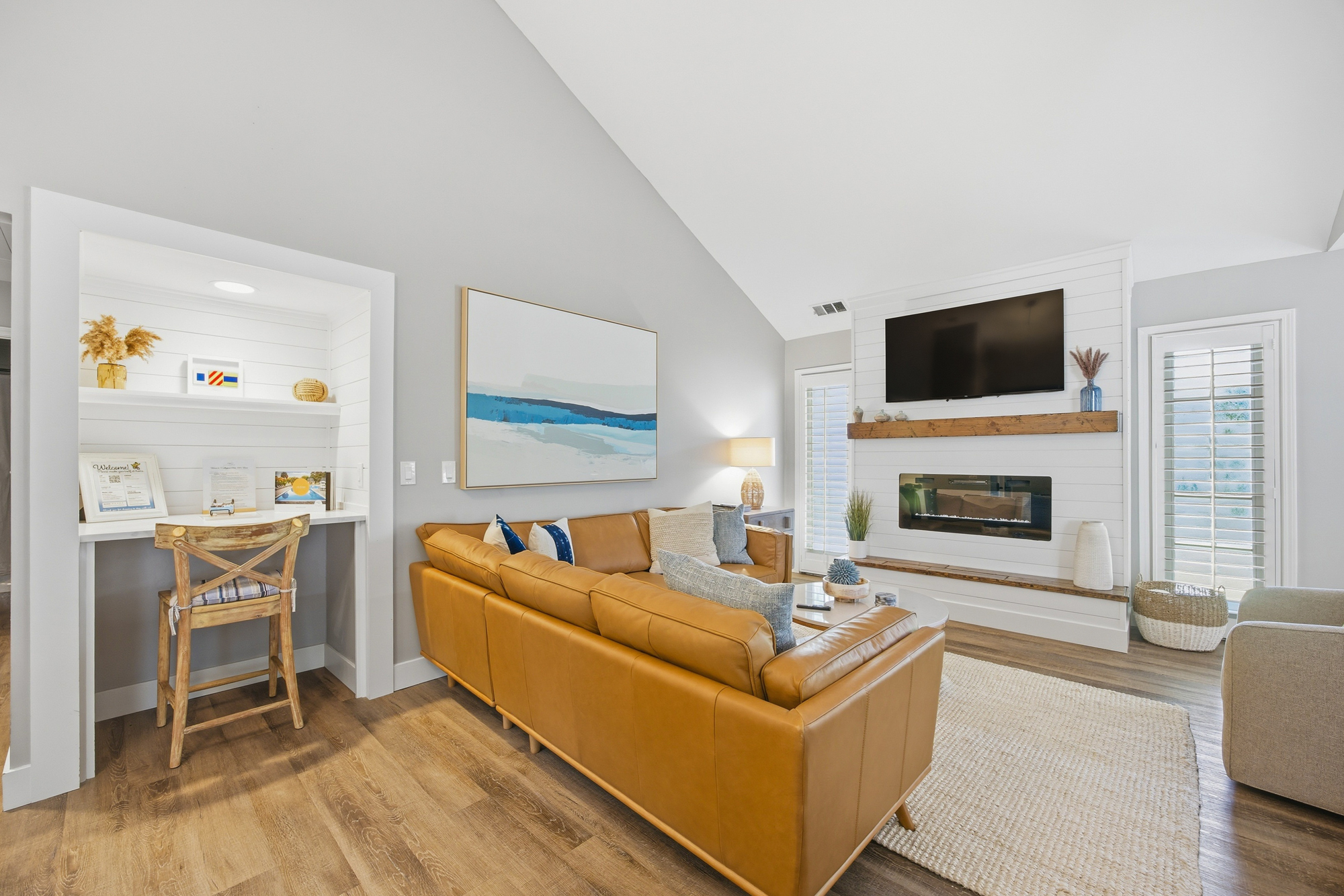 Cognac leather and warm wood accents ground this airy living room, where a sleek fireplace and coastal art create a serene mood. Settle into the plush sectional for movie night or catch up on emails at the charming built-in desk nook.