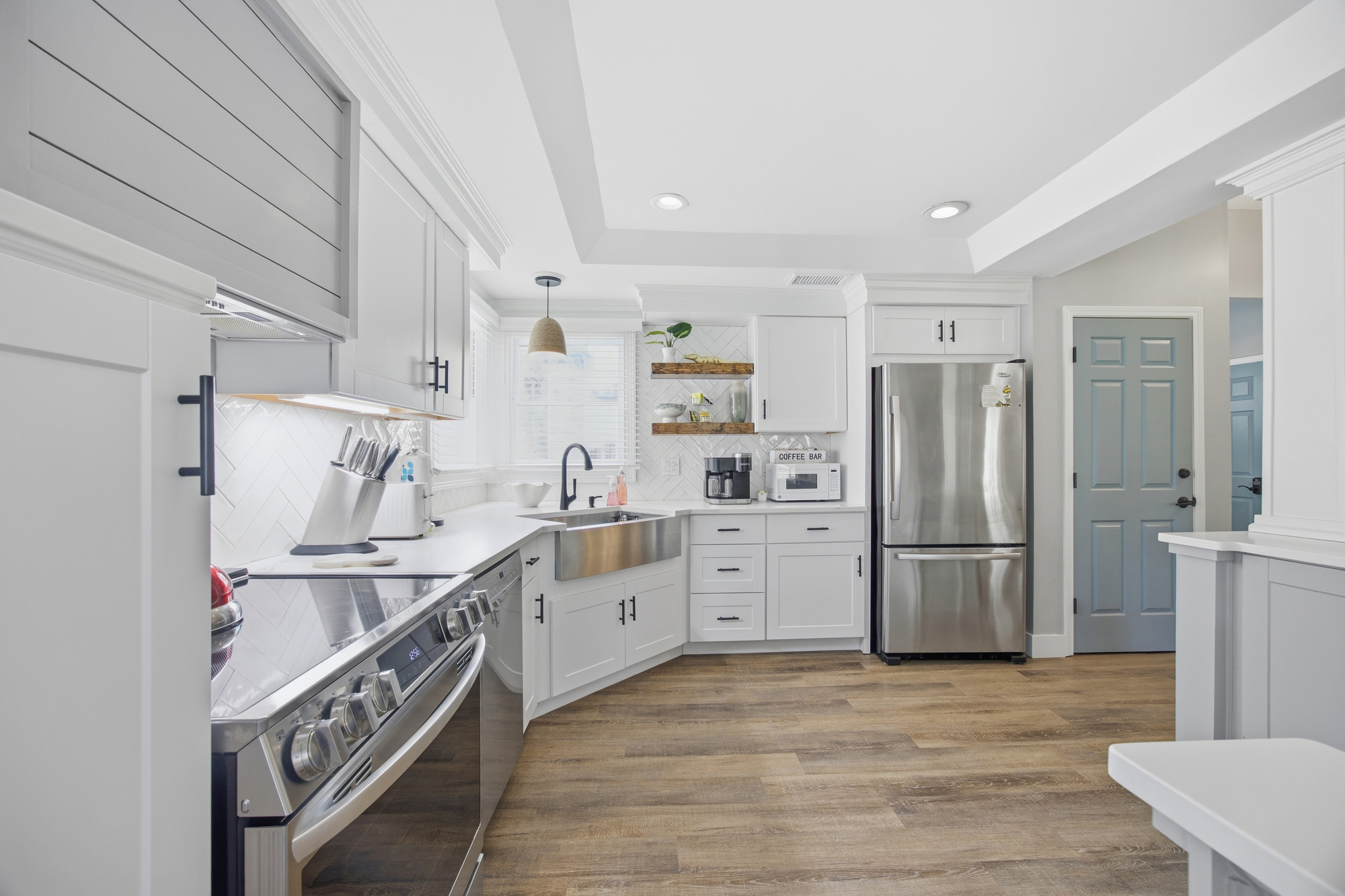 Bright cabinetry and warm wood floors frame this chef-ready kitchen, where a farmhouse sink and modern appliances wait for your morning coffee. Natural light floods the workspace, creating a fresh and airy setting for every meal.
