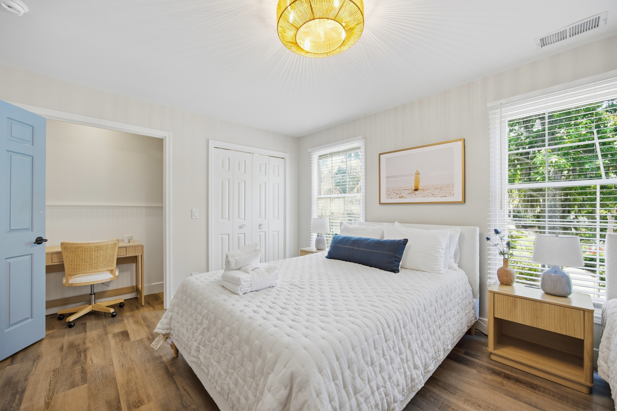 Soft textures and natural oak tones ground this airy bedroom, where morning rays filter through white slats. A rattan pendant light casts a honeyed glow over the plush bedding and a quiet desk nook tucked away for peaceful afternoon focus.