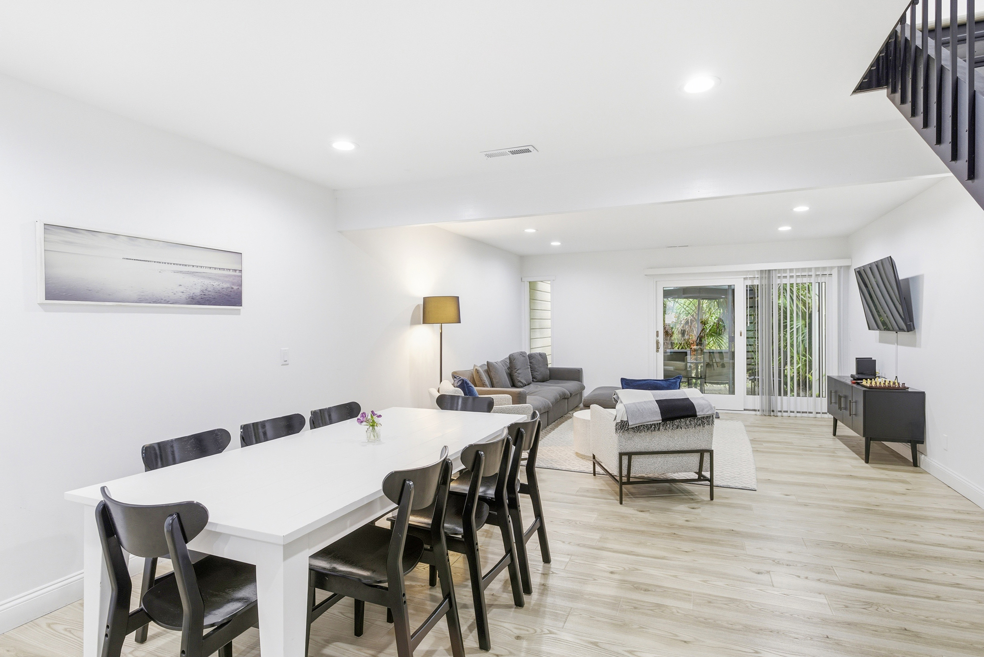Polished wood floors lead the eye through this airy open space, where a long white dining table meets a cozy lounge. Soft illumination and minimalist decor create a calm, sophisticated atmosphere perfect for slow mornings and shared meals.