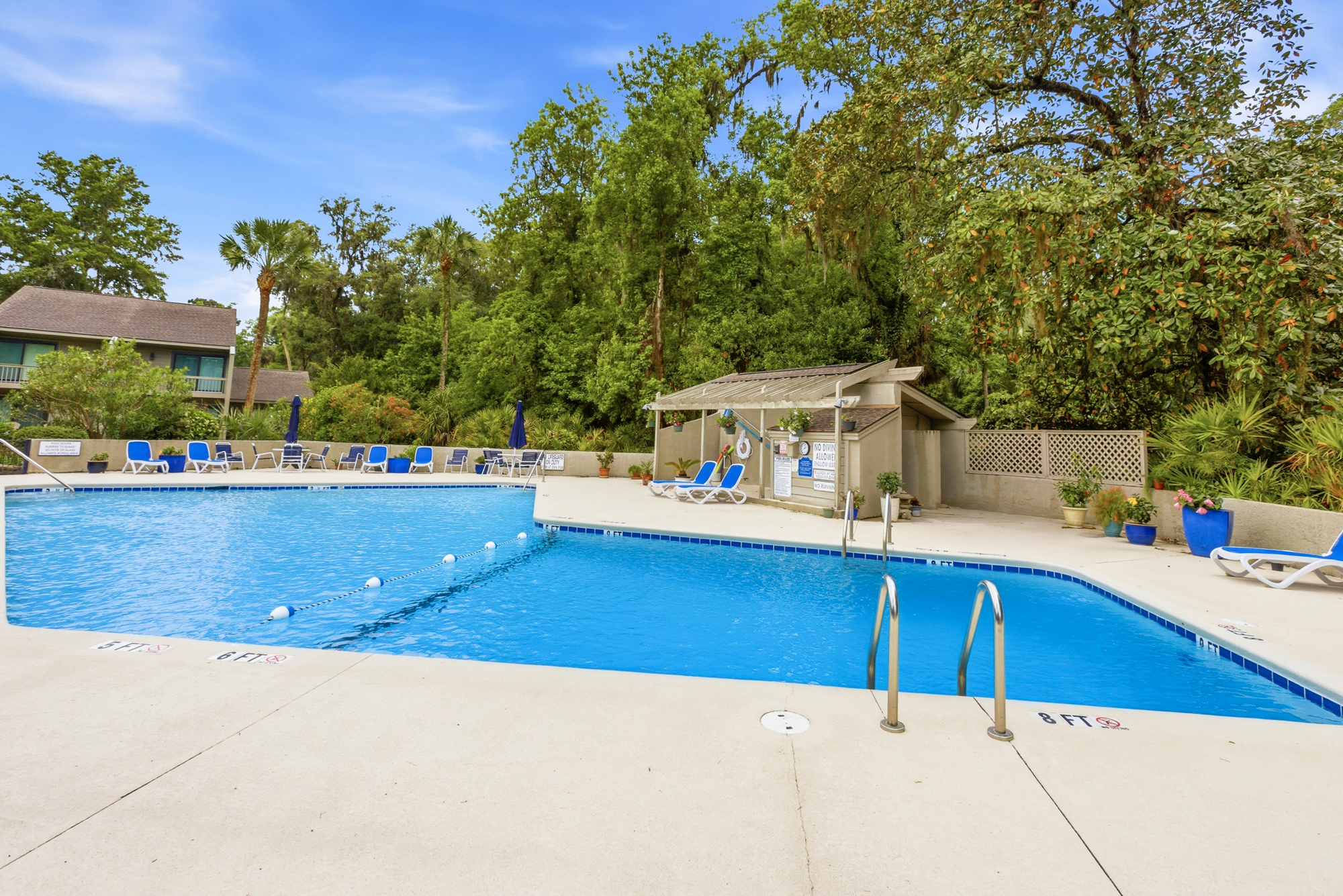 Sparkling turquoise waters await under a canopy of lush oak trees and Spanish moss. This expansive pool deck offers a peaceful escape where the afternoon glow warms the smooth stone and invites you for a quiet afternoon swim.