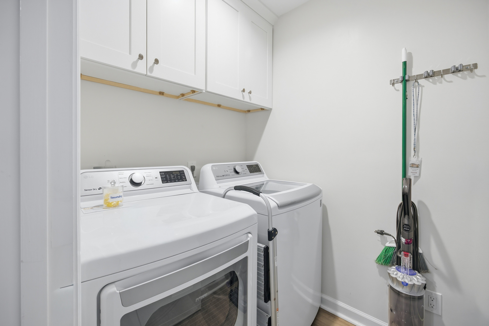 Bright white cabinetry and modern appliances create a fresh, orderly laundry nook. This functional corner offers every convenience needed for a seamless stay, tucked away in a neat and airy space.