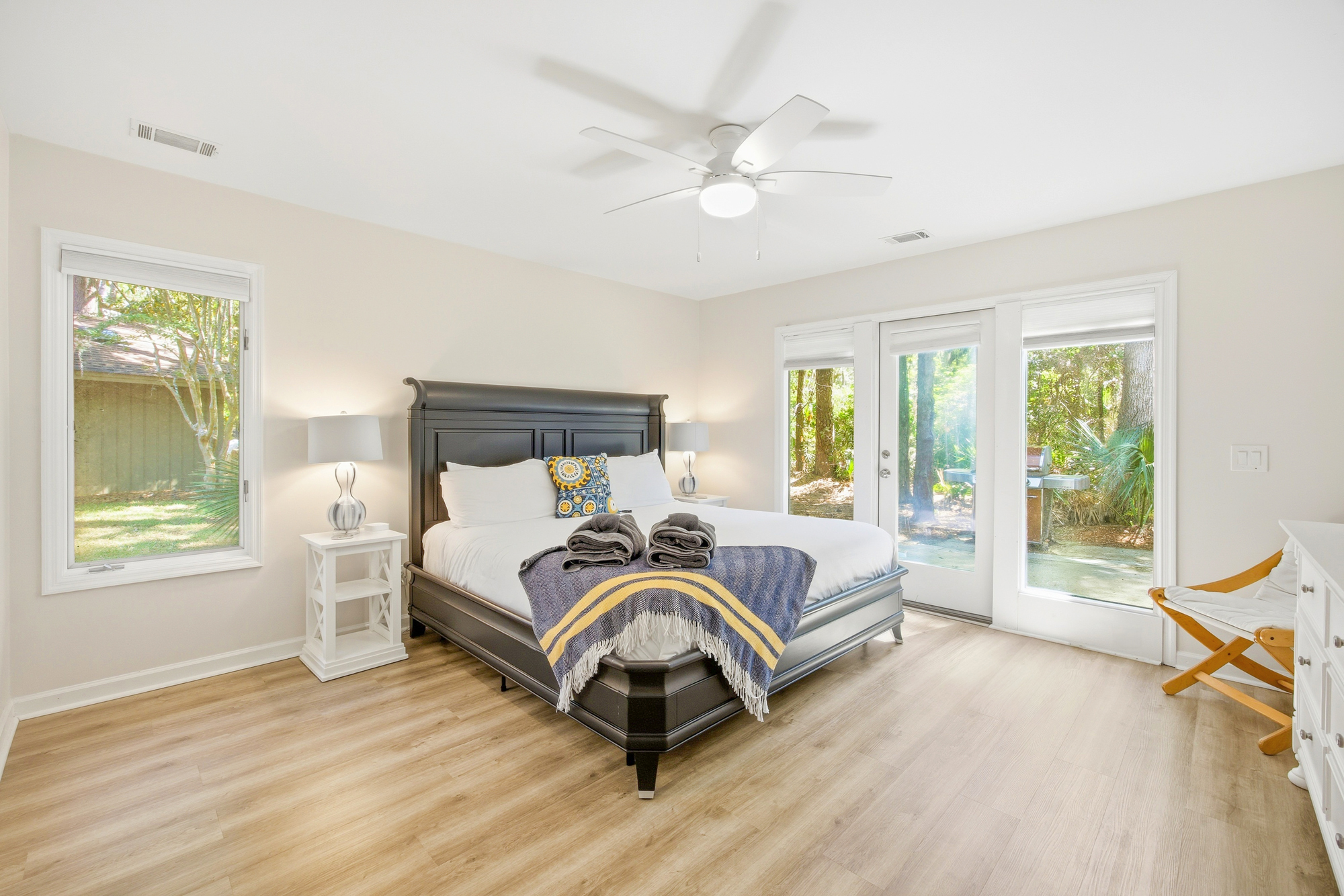 Floor-to-ceiling glass doors draw the quiet beauty of the woods inside this airy suite. Bright walls and smooth wood floors create a serene backdrop for a restful night in the plush, king-sized sleigh bed.