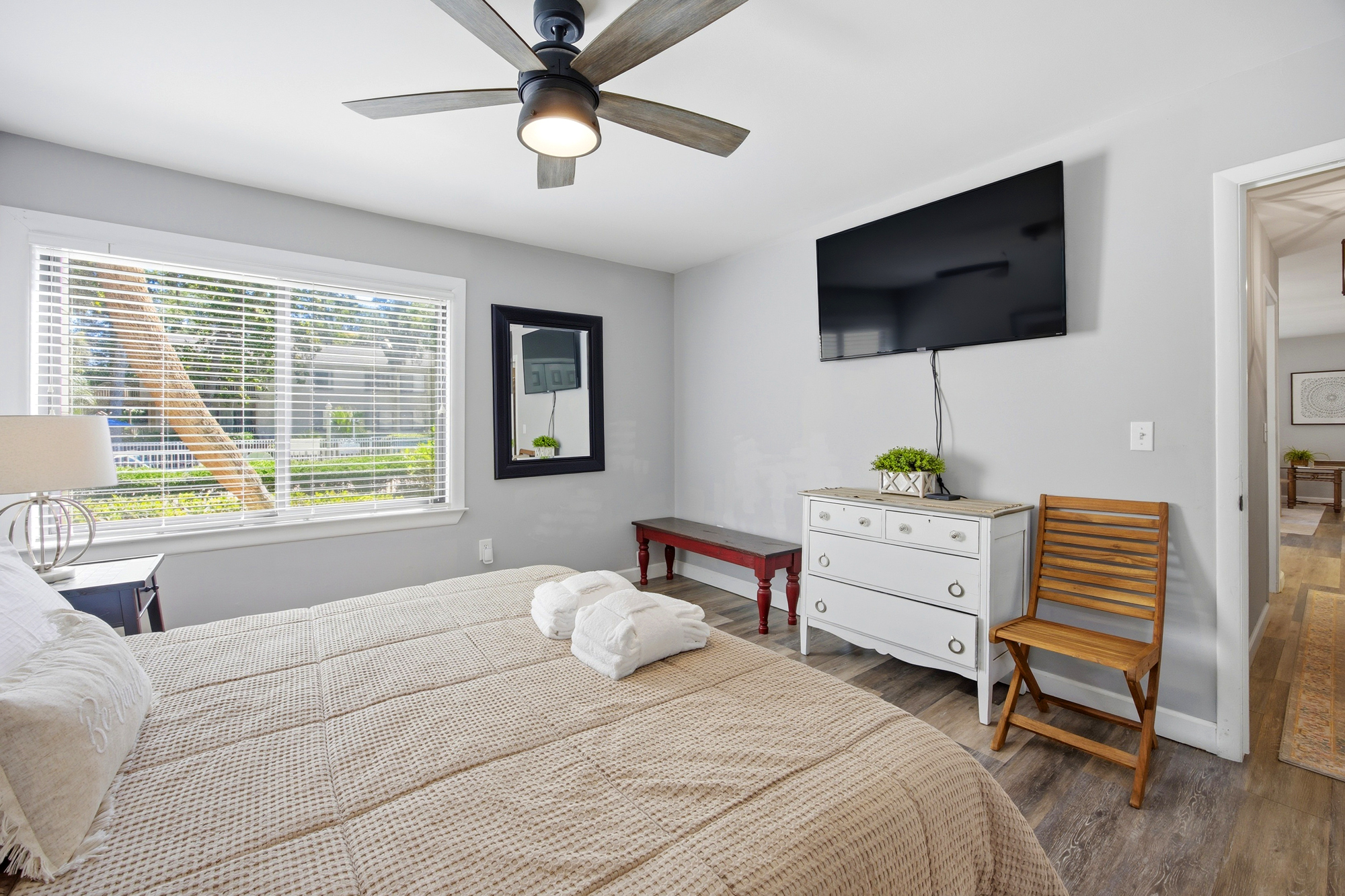 Natural morning glimmers play across the textured waffle bedding and rustic wood accents. This serene bedroom pairs cool gray walls with a charming white dresser, creating a quiet space for a peaceful afternoon rest.