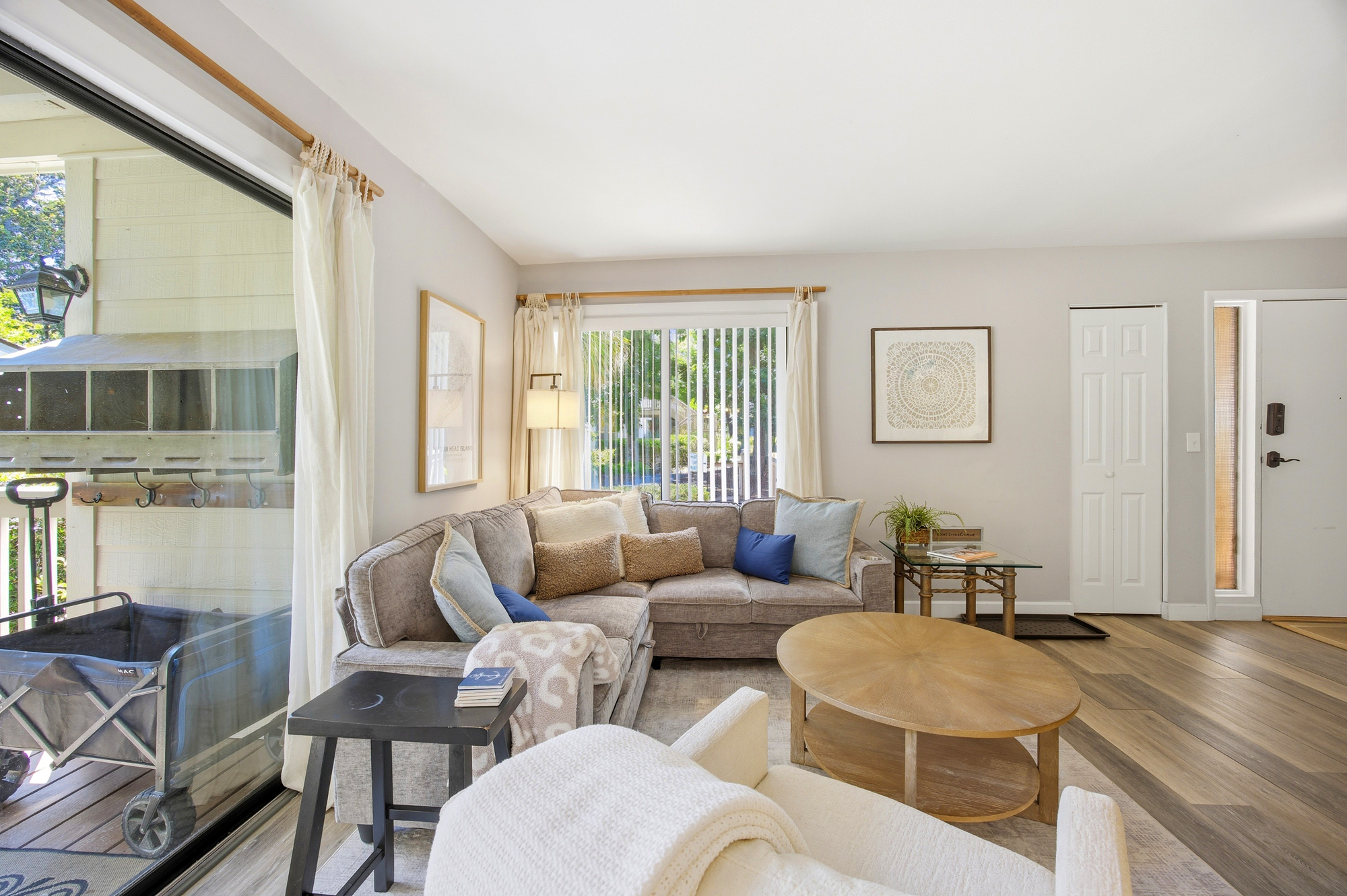 Plush seating and wood accents create a peaceful corner for quiet afternoons. Gentle daylight filters through airy curtains, highlighting the earthy tones and textured throws that make this inviting lounge feel like home.