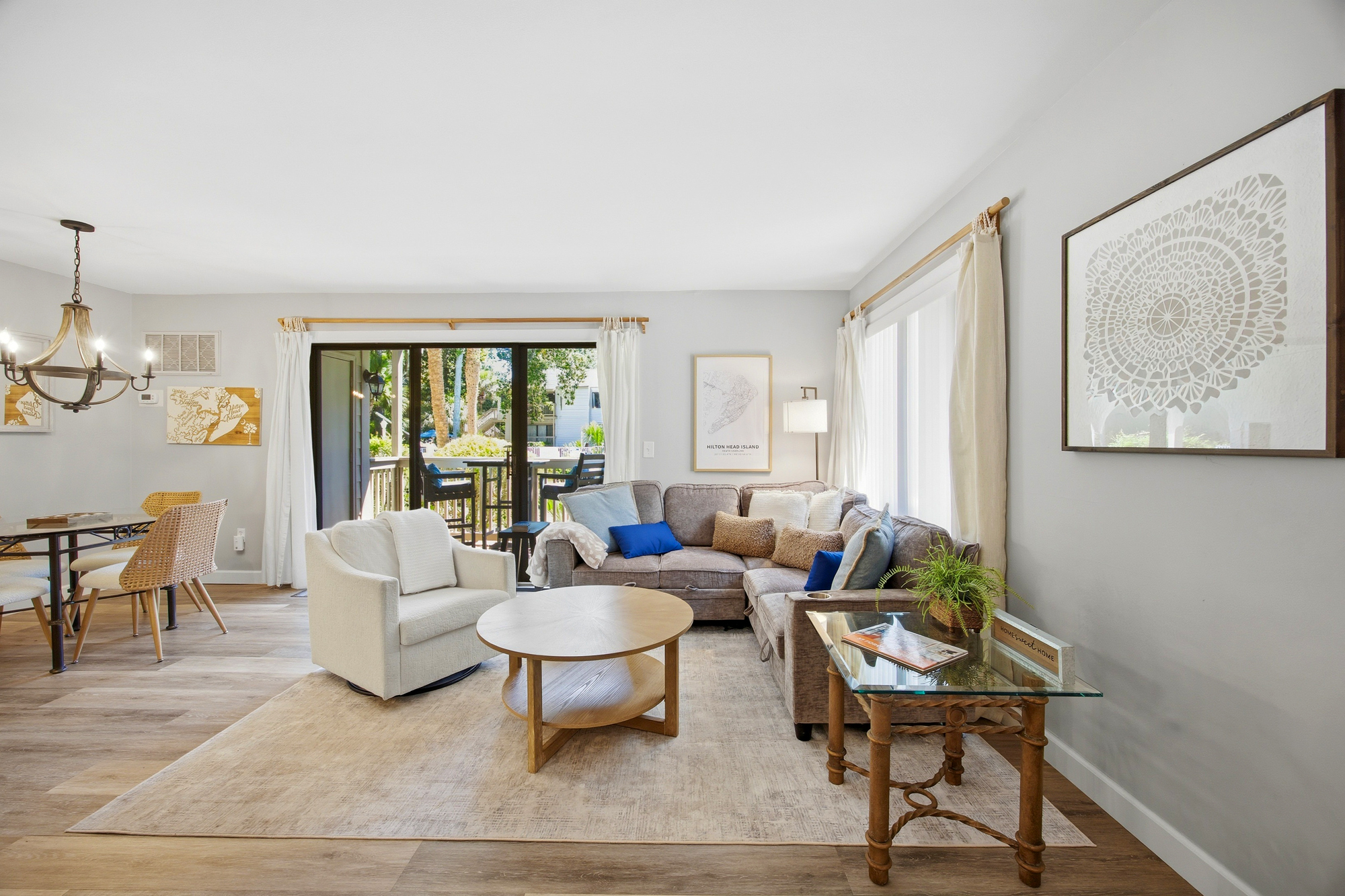 Azure accents and golden wood tones brighten this airy living space, where large glass doors pull the outdoors in. Sink into the sectional for a quiet afternoon of reading or host a dinner under the glow of the iron chandelier.