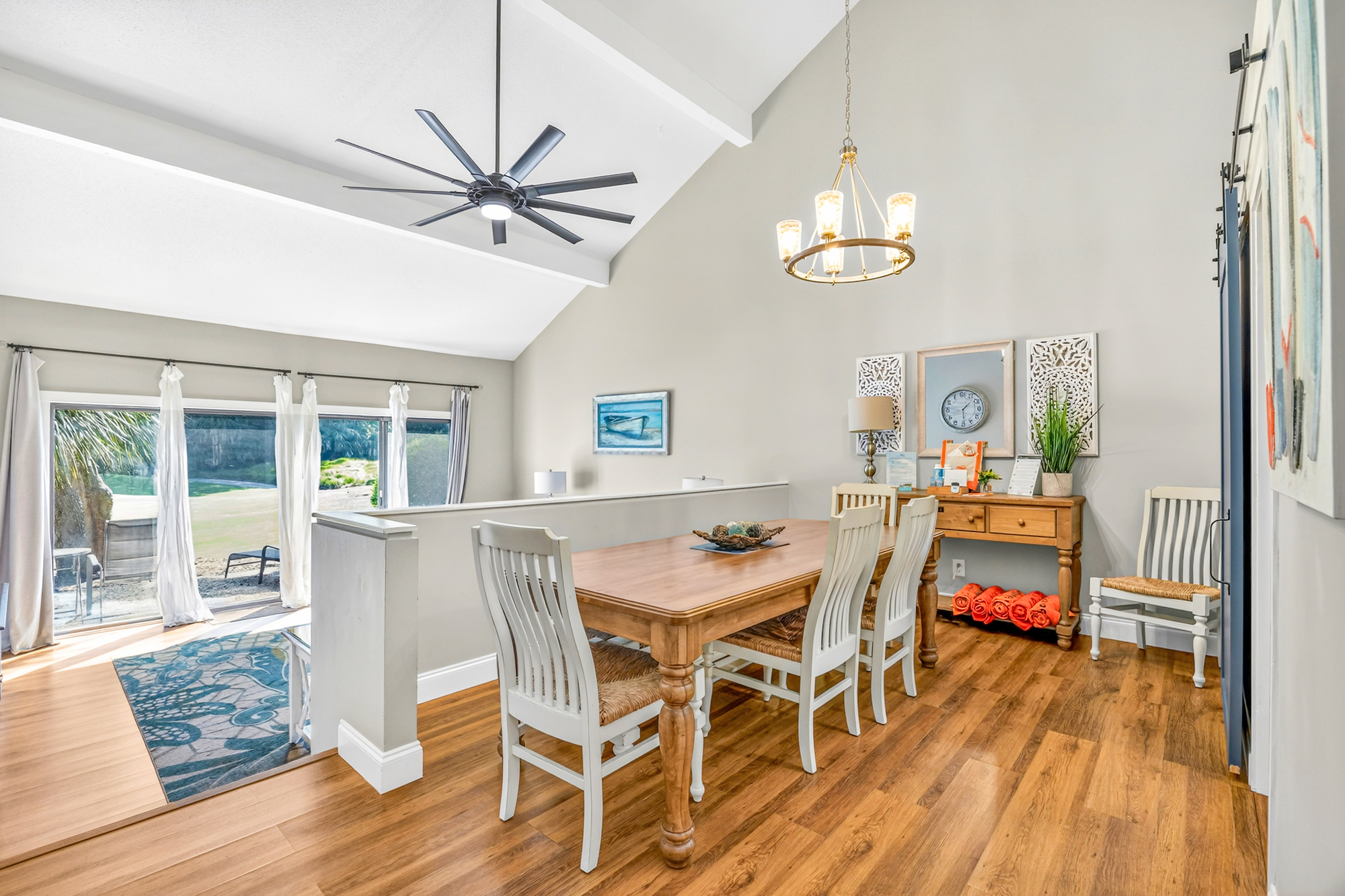 High ceilings and airy white beams create a sense of grandeur over the spacious dining area. Rich timber floors catch the afternoon glow, while coastal accents and plush seating invite slow mornings with coffee and conversation.