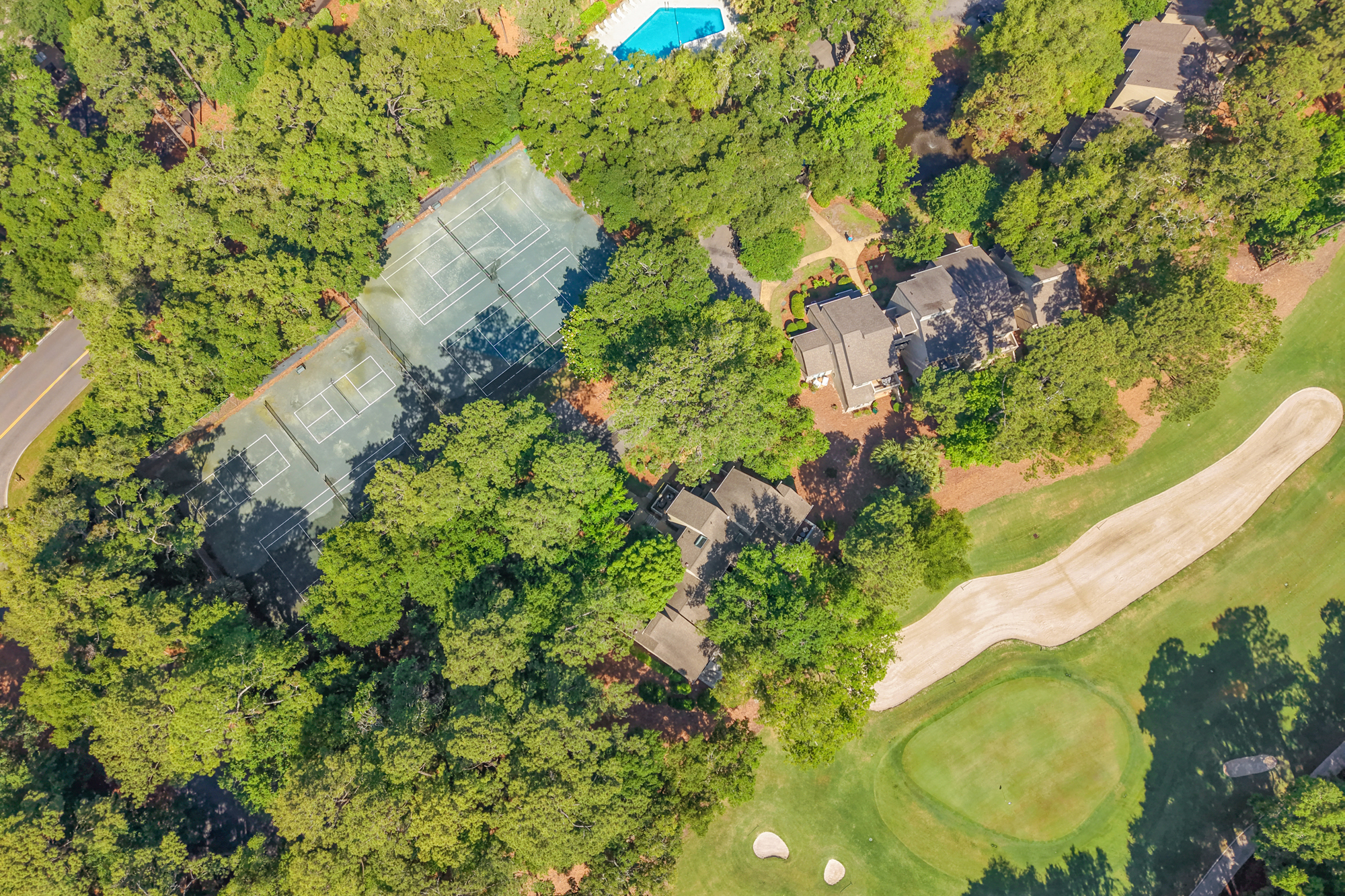 Verdant treetops canopy our private tennis courts and sparkling pool, offering a peaceful aerial view of the resort grounds. Emerald fairways stretch beyond the villas, inviting you to spend slow afternoons in the fresh coastal air.