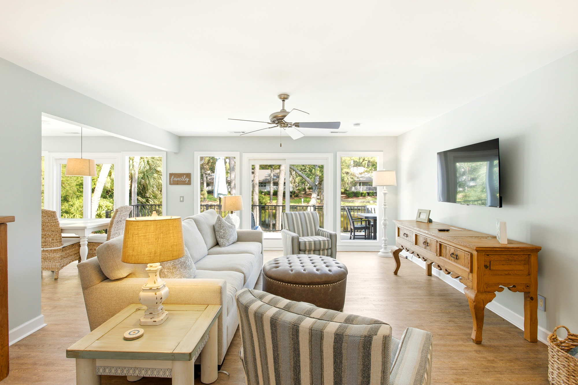 Honey-toned wood and plush seating fill this airy living room with a serene glow. Large windows frame views of the lush greenery outside, while warm lamps create a cozy atmosphere perfect for quiet evenings after a day of exploring.