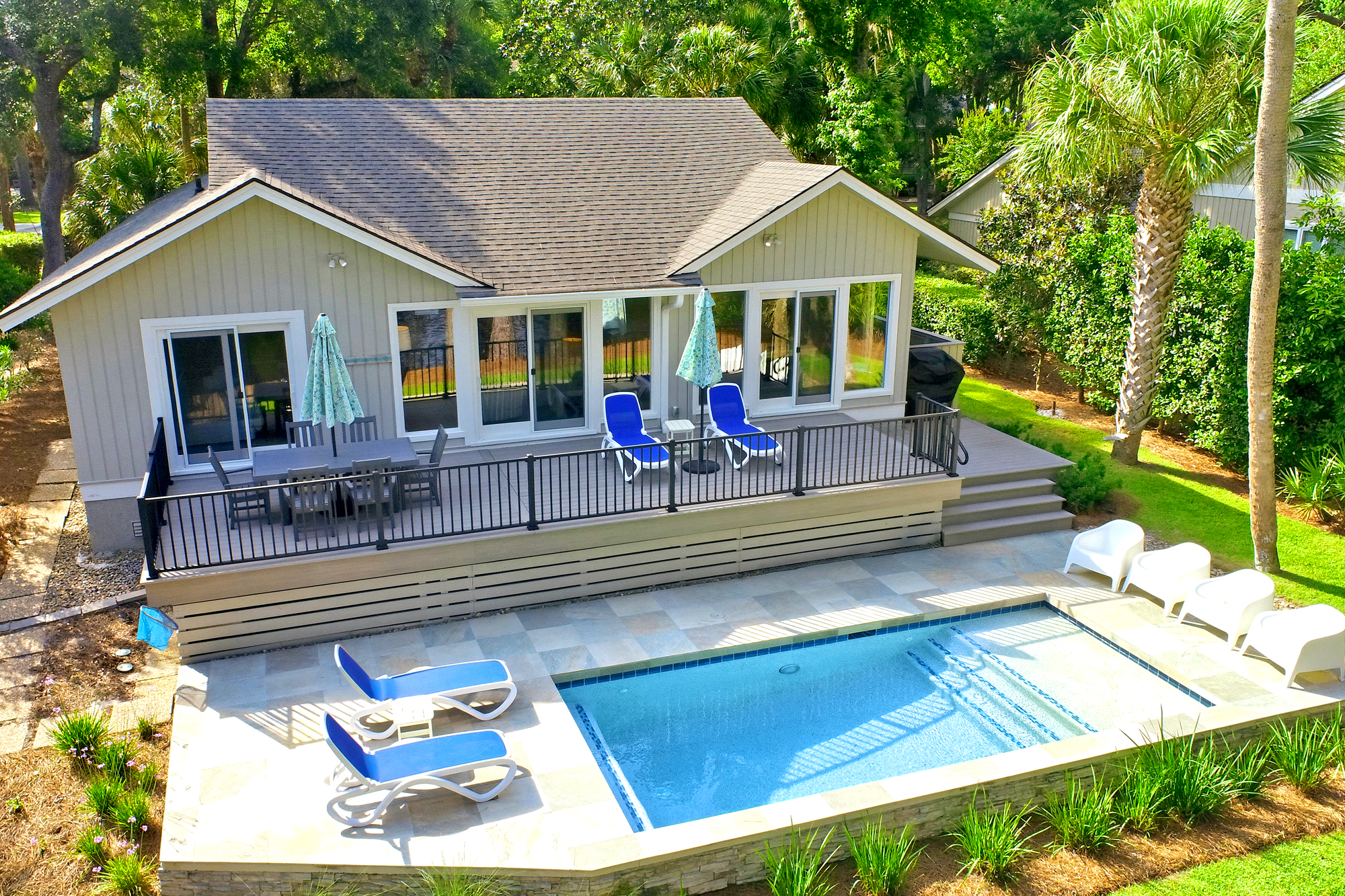 Sparkling blue water anchors this private poolside terrace, where sun-drenched stone tiles meet lush tropical greenery. Glass doors open wide to a spacious deck, creating a seamless flow for afternoon swims and alfresco dining under the palms.