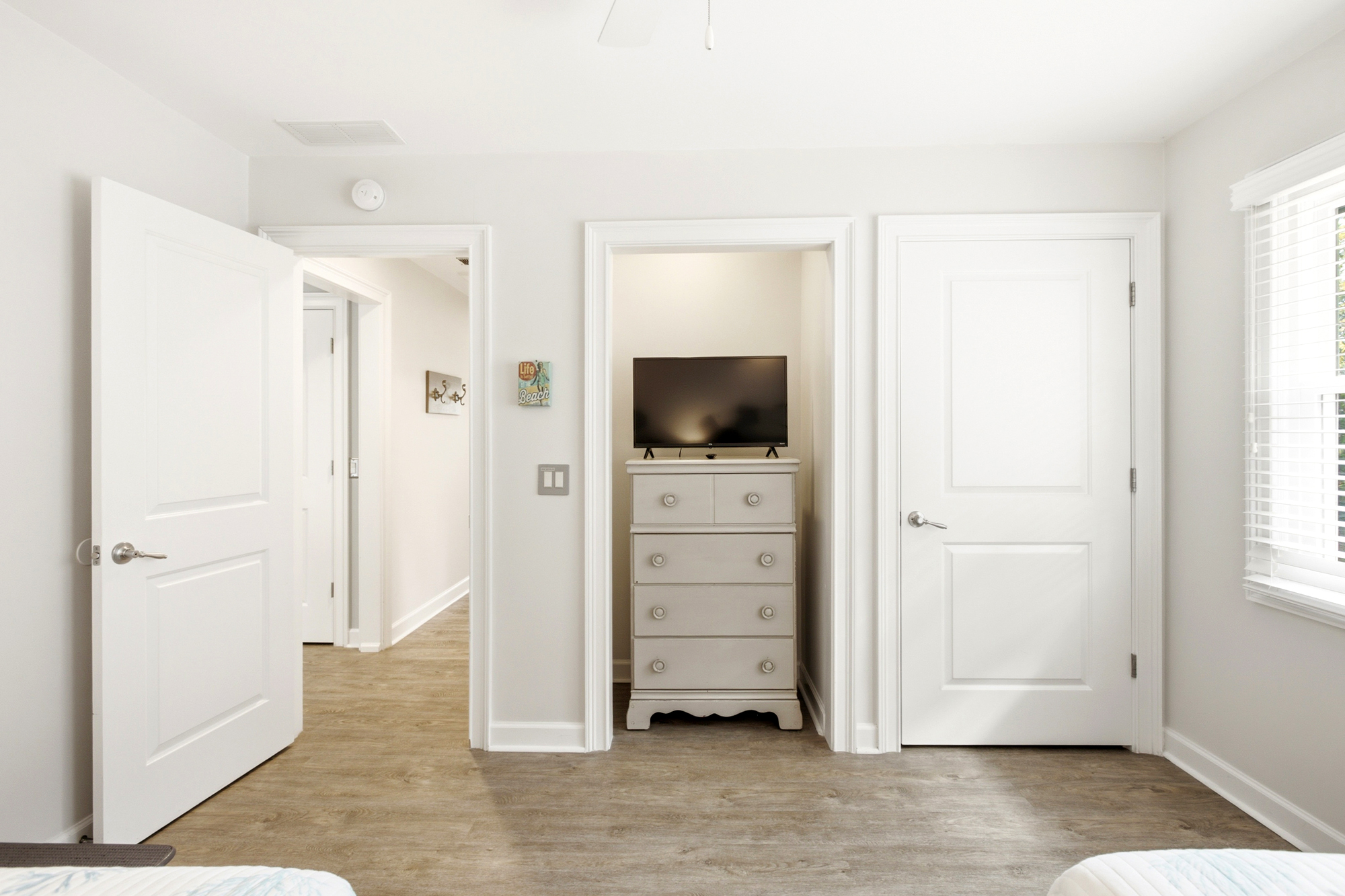 Ivory walls and warm timber floors create a calm, airy atmosphere in this quiet corner. Afternoon beams play across the clean molding and clever built-in nook, offering a peaceful space to decompress after a day of adventure.