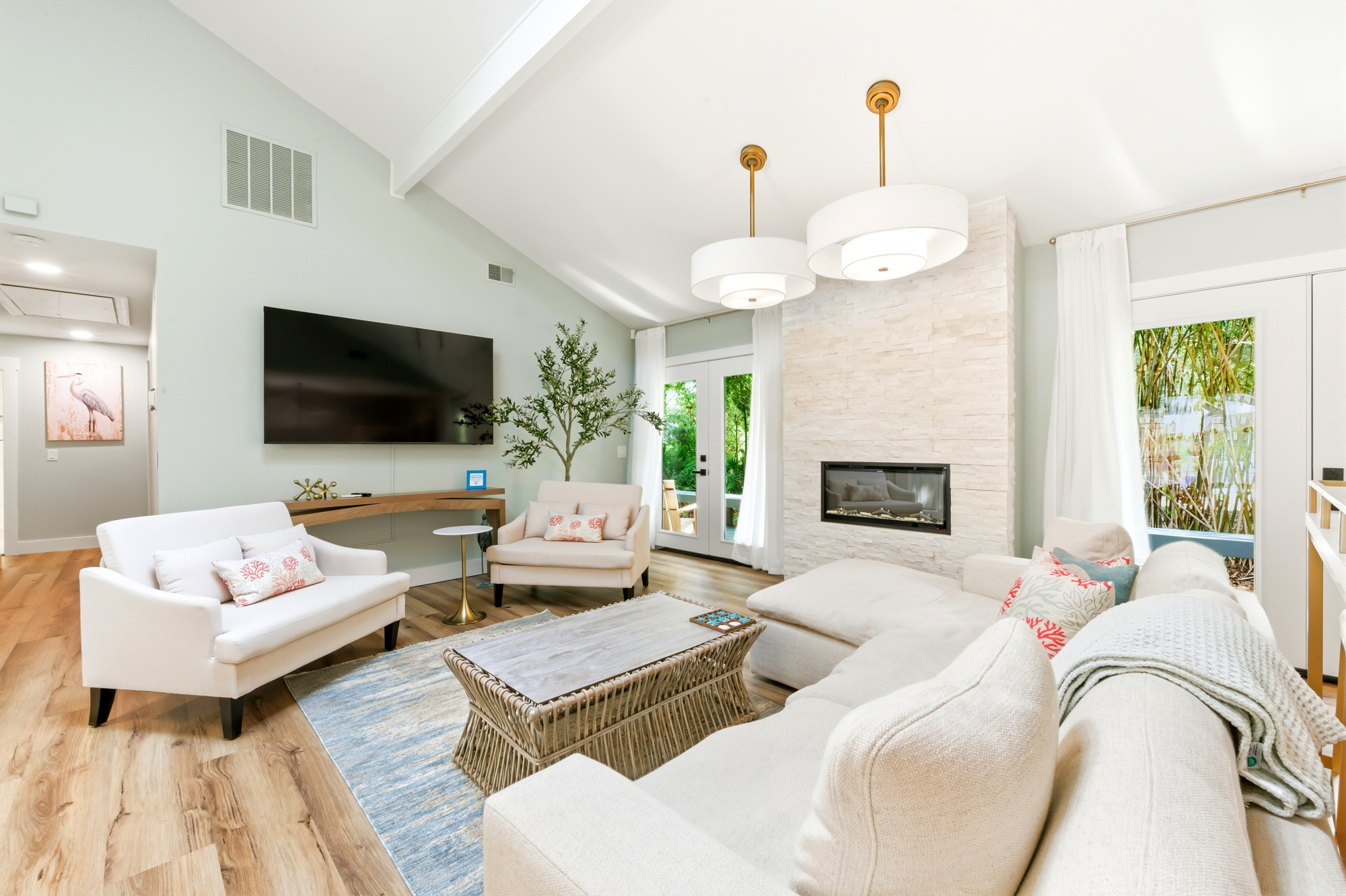Stone tile textures and vaulted ceilings create an airy backdrop for an evening by the fire. Soft upholstery and natural wood tones invite you to linger in this sun-drenched living area, where garden views peek through the glass doors.
