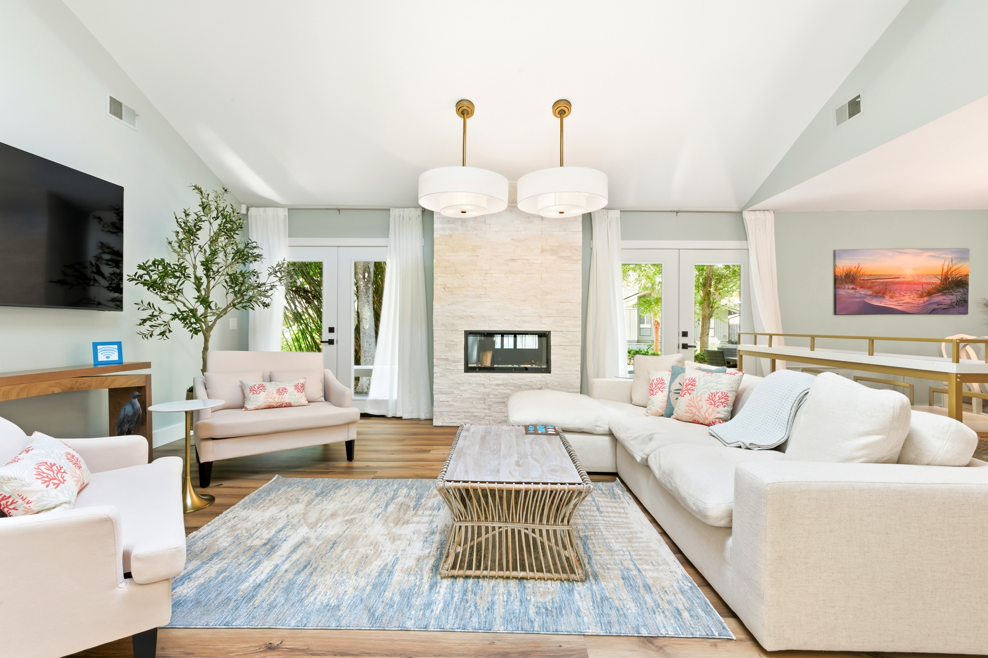 Coastal hues and airy vaulted ceilings create a serene backdrop for slow mornings by the stone fireplace. Natural textures and plush seating invite you to linger in the soft glow of this sun-drenched living space.