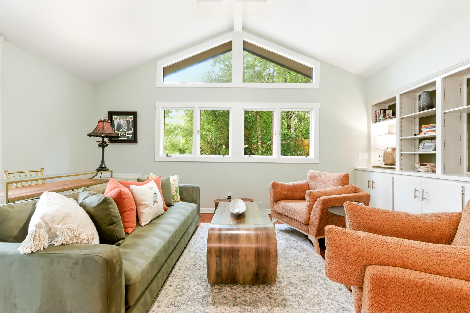 High ceilings and clerestory windows pull the leafy outdoors into this airy lounge. Earthy velvet and textured terra cotta seating frame a sculpted wood table, creating a serene spot illuminated by soft afternoon brightness.
