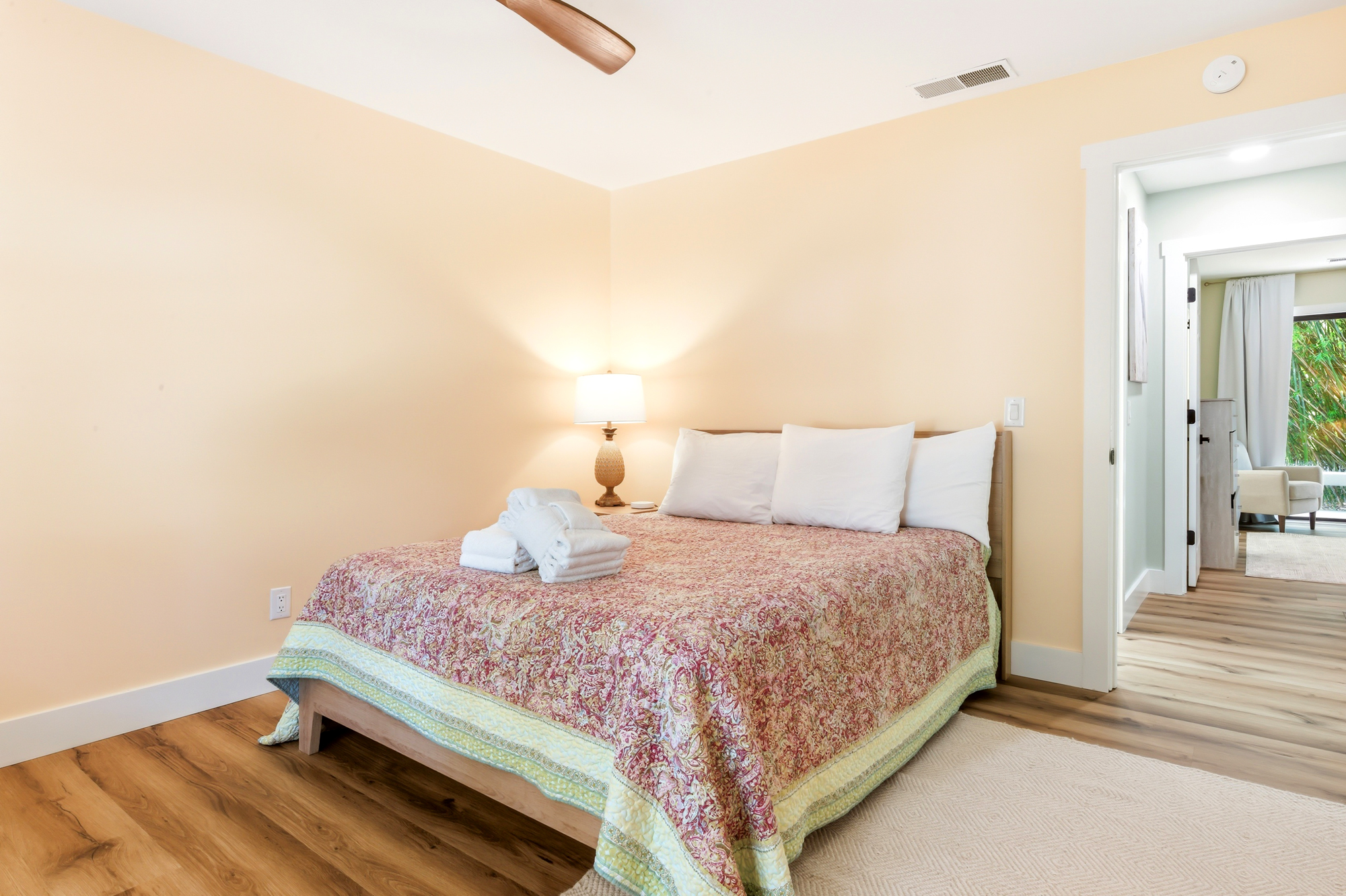 Honey-hued walls and grain-rich floors anchor this cozy bedroom, where a patterned quilt adds a touch of charm. The gentle glow from a bedside lamp creates a quiet nook for rest.