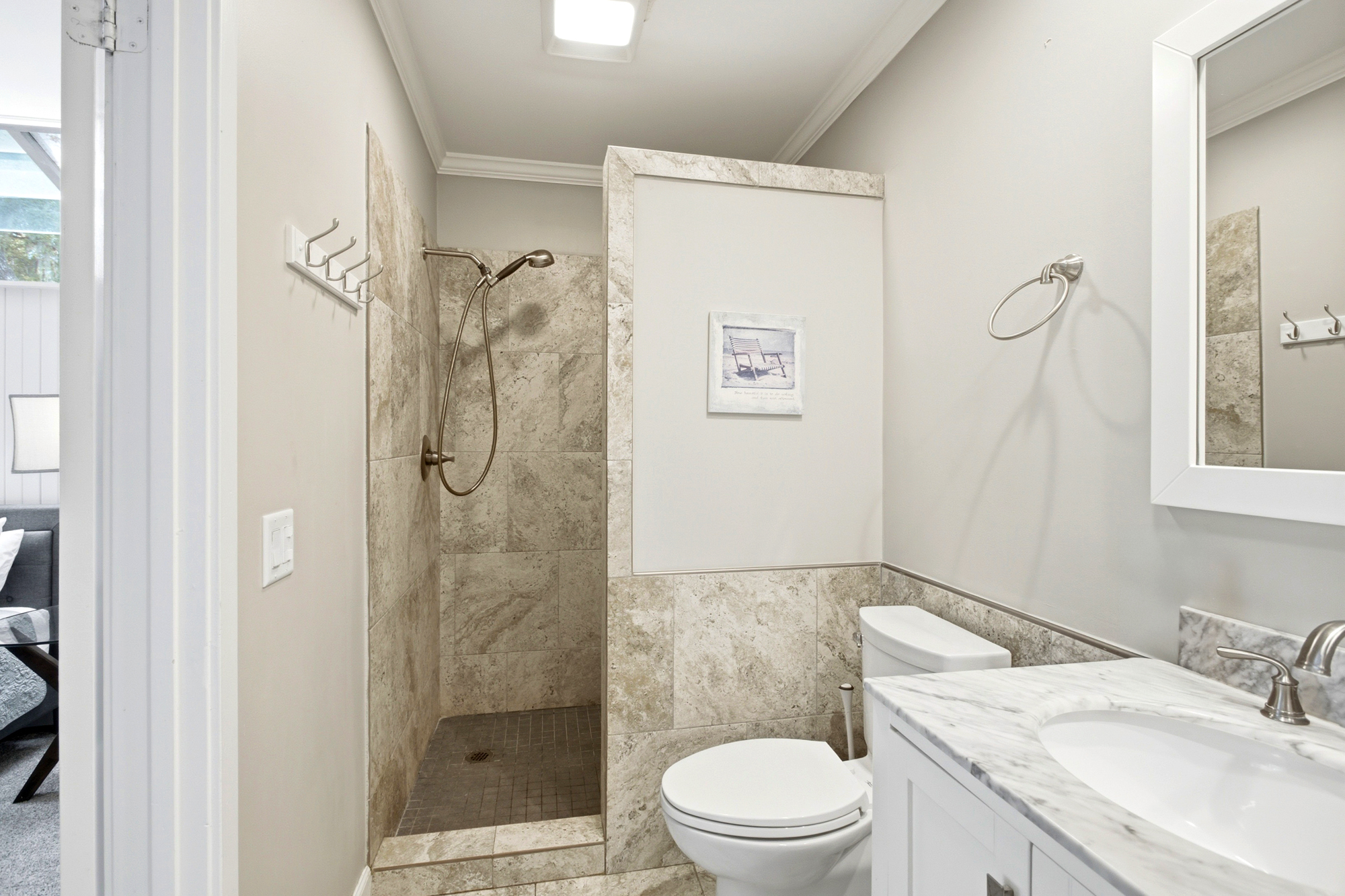 Earth-toned tiles and a marble-topped vanity create a spa-like sanctuary for your morning routine. Brushed nickel fixtures and clean, white lines make this compact bathroom feel bright, airy, and impeccably refreshed.