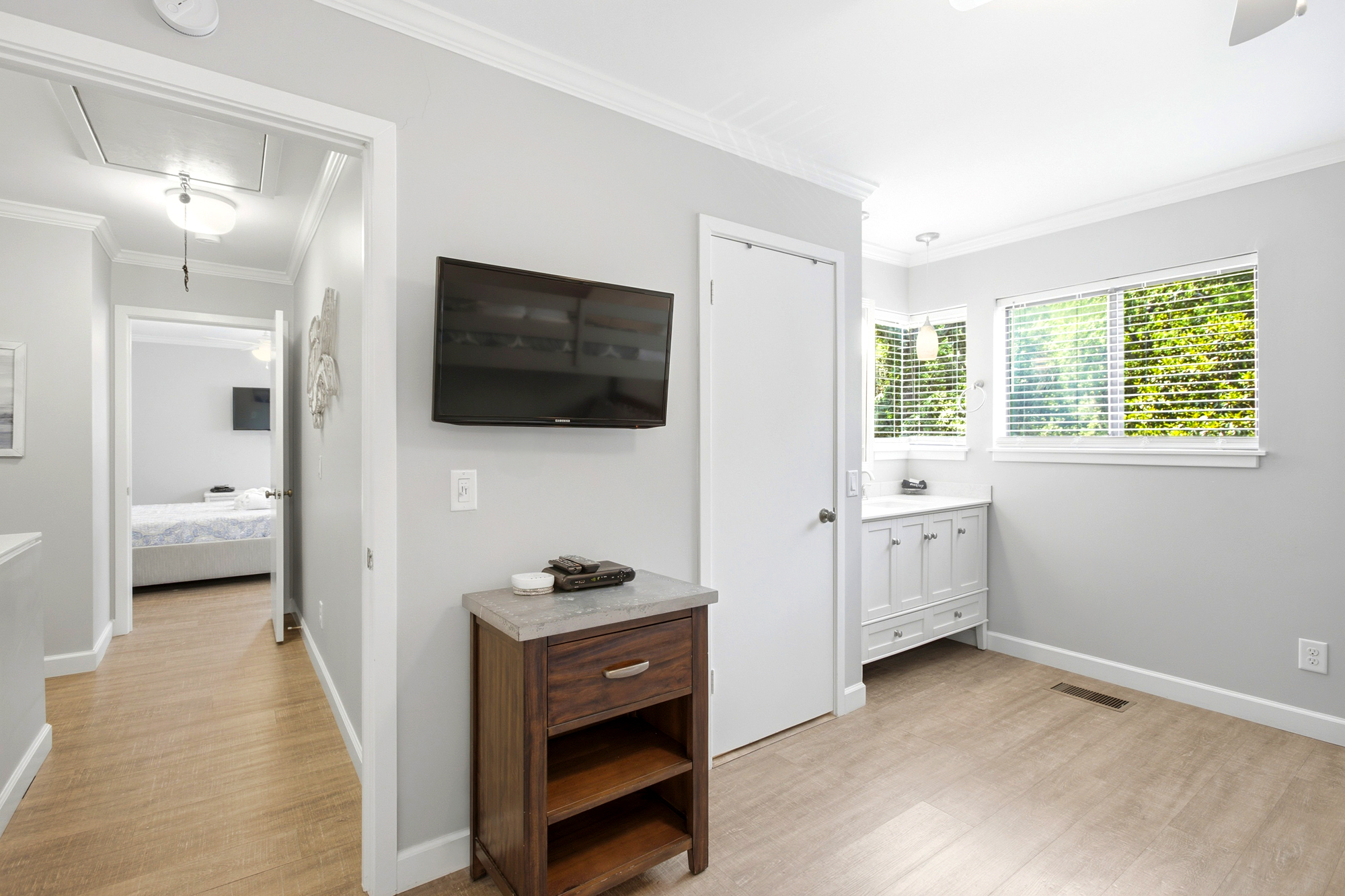 Morning radiance streams through wide windows, illuminating the clean lines of this airy suite. Warm wood floors and a sleek vanity create a serene corner for your daily routine.