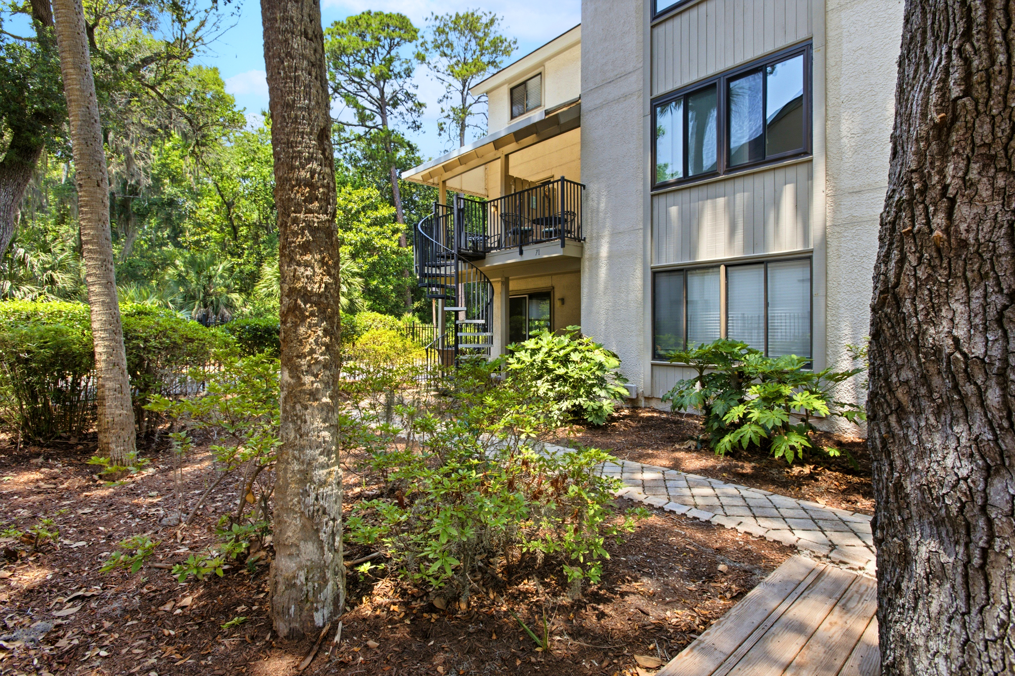 Sturdy oaks and winding stone paths lead to this quiet villa, where a spiral staircase climbs toward a private balcony. Sun-drenched gardens wrap around the modern facade, creating a secluded sanctuary for your morning coffee.