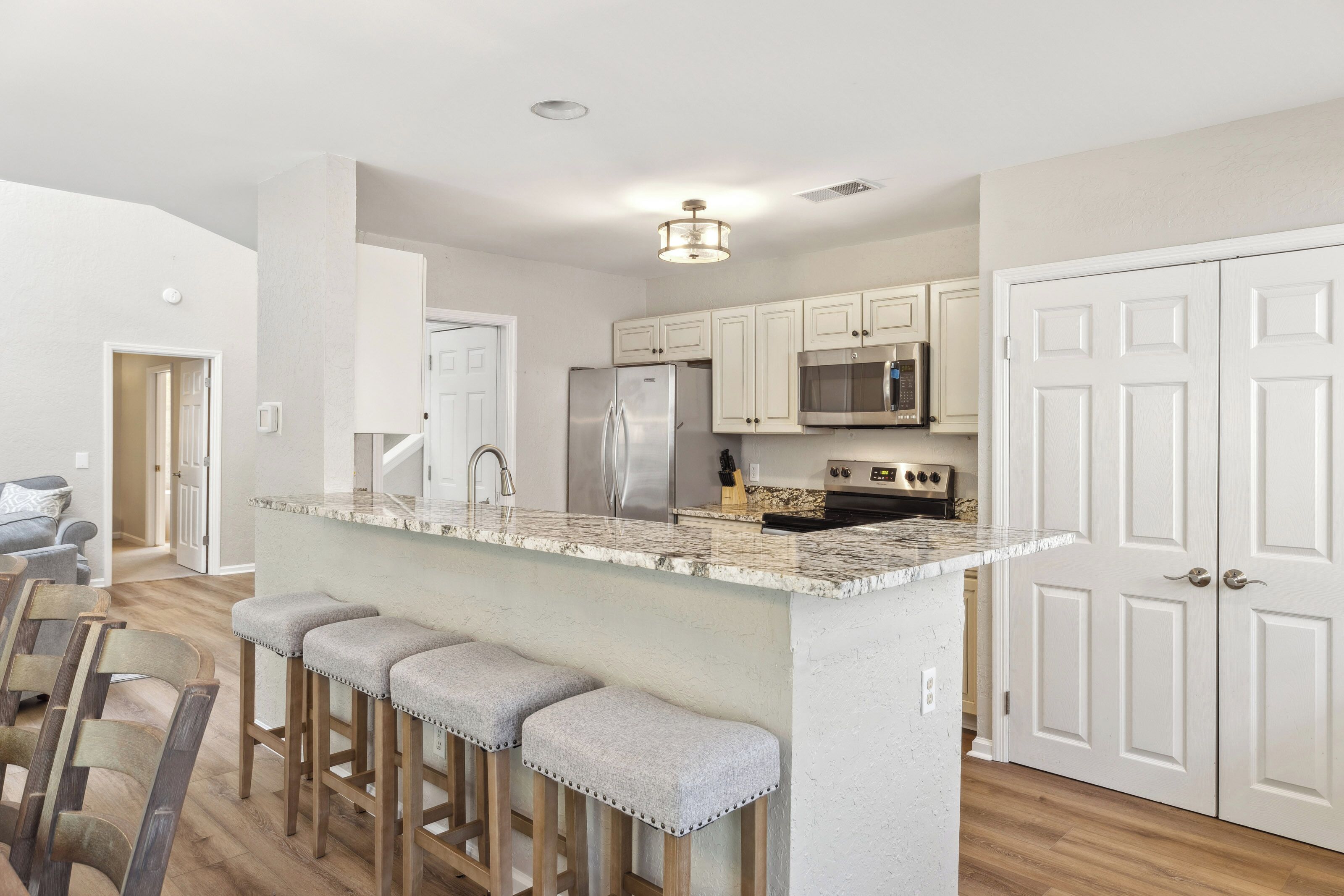 Stone surfaces and cushioned seating invite you to linger over coffee in this open kitchen. Soft hues and modern appliances create a seamless blend of comfort and utility for your morning routine.
