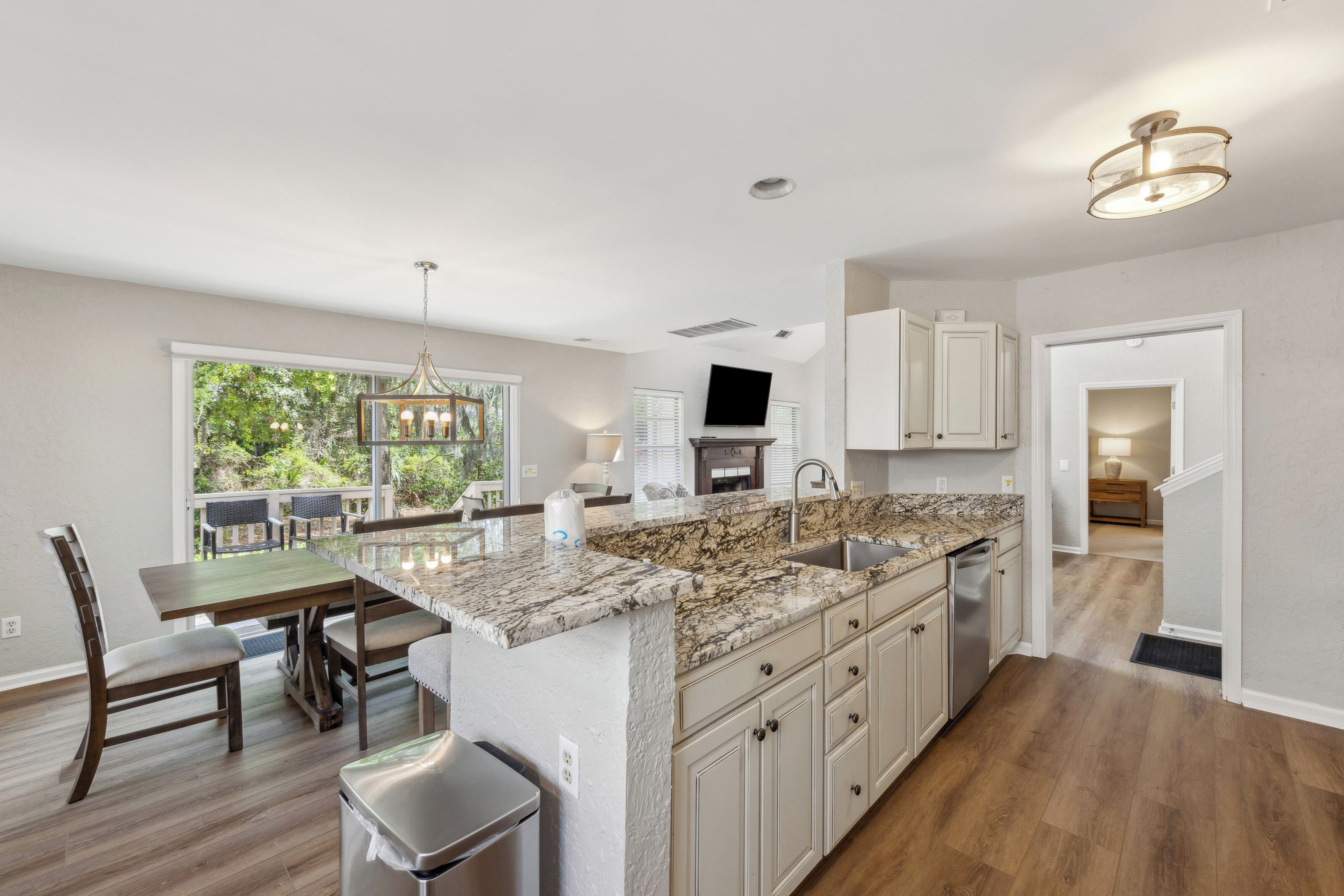 Lustrous countertops wrap around this open chef's kitchen, where soft glow meets views of the lush greenery outside. Gather for coffee at the breakfast bar or share a meal in the sunlit dining area overlooking the trees.