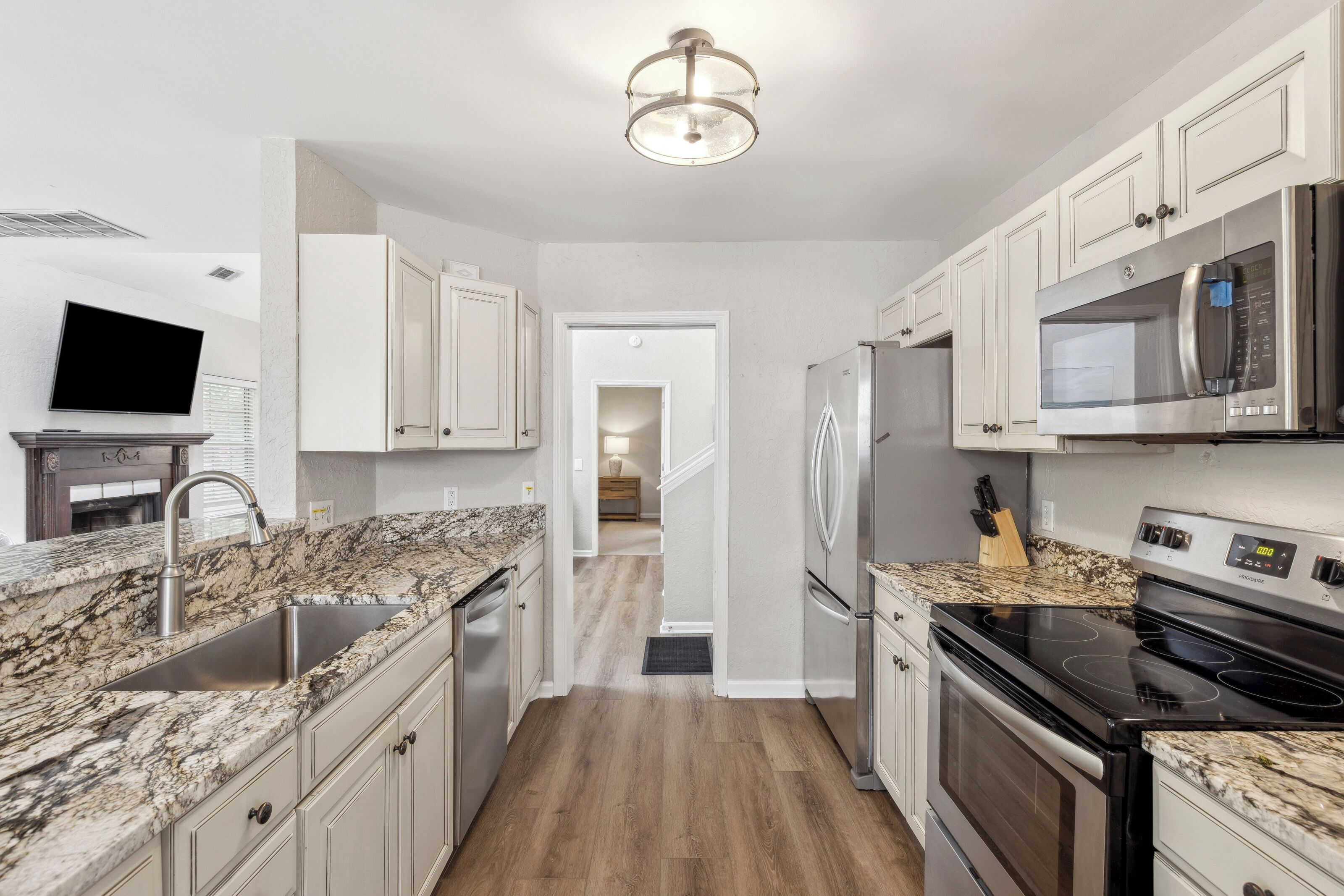 Creamy cabinetry and textured surfaces create a soft, inviting atmosphere for your morning coffee. Modern stainless steel appliances pair beautifully with rich wood-toned flooring to make this heart of the home both stylish and functional.
