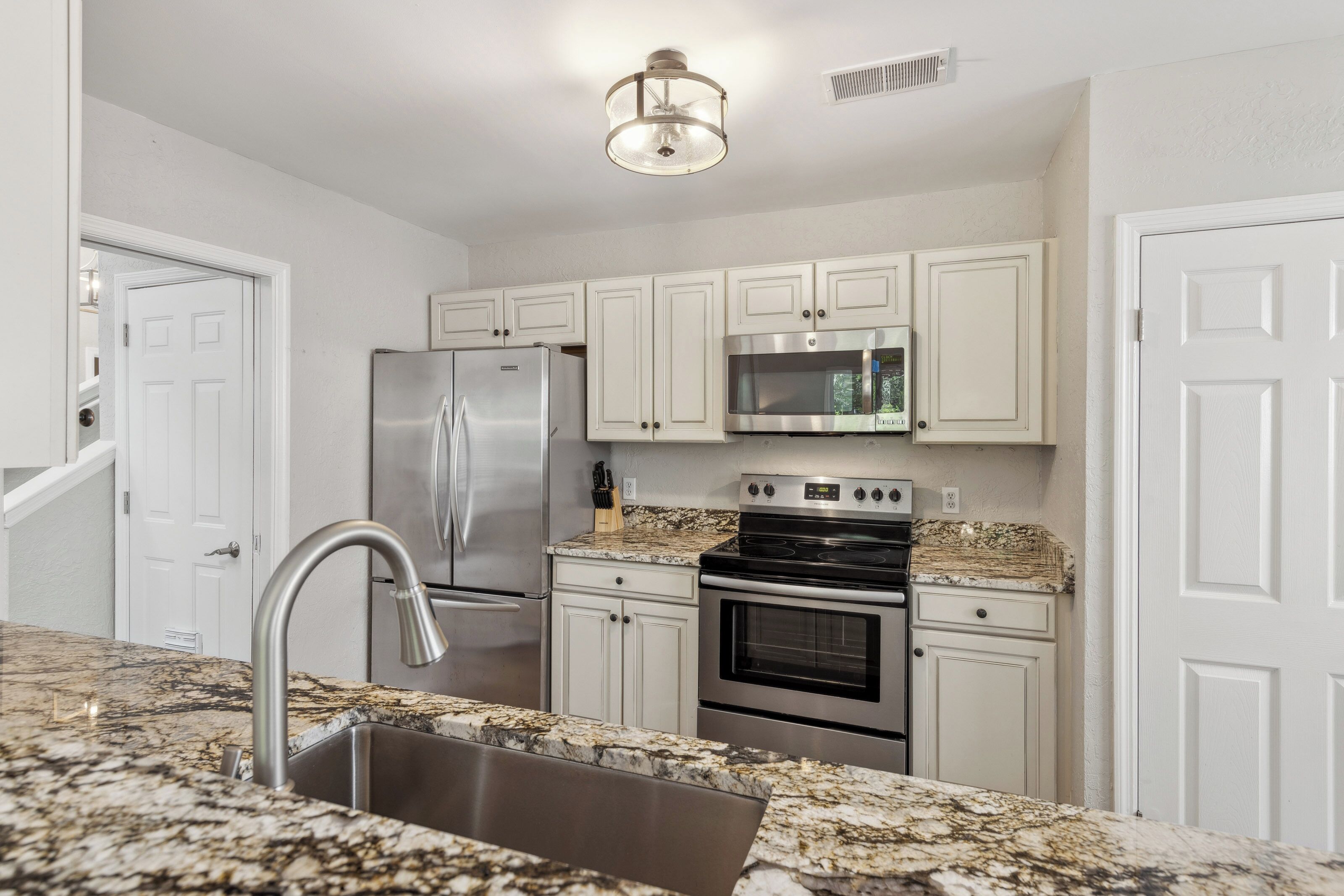 Stainless steel appliances meet detailed counter surfaces in this efficient kitchen. Soft overhead illumination catches the subtle textures of the cabinetry, creating a calm and clean atmosphere for preparing your favorite morning meals.