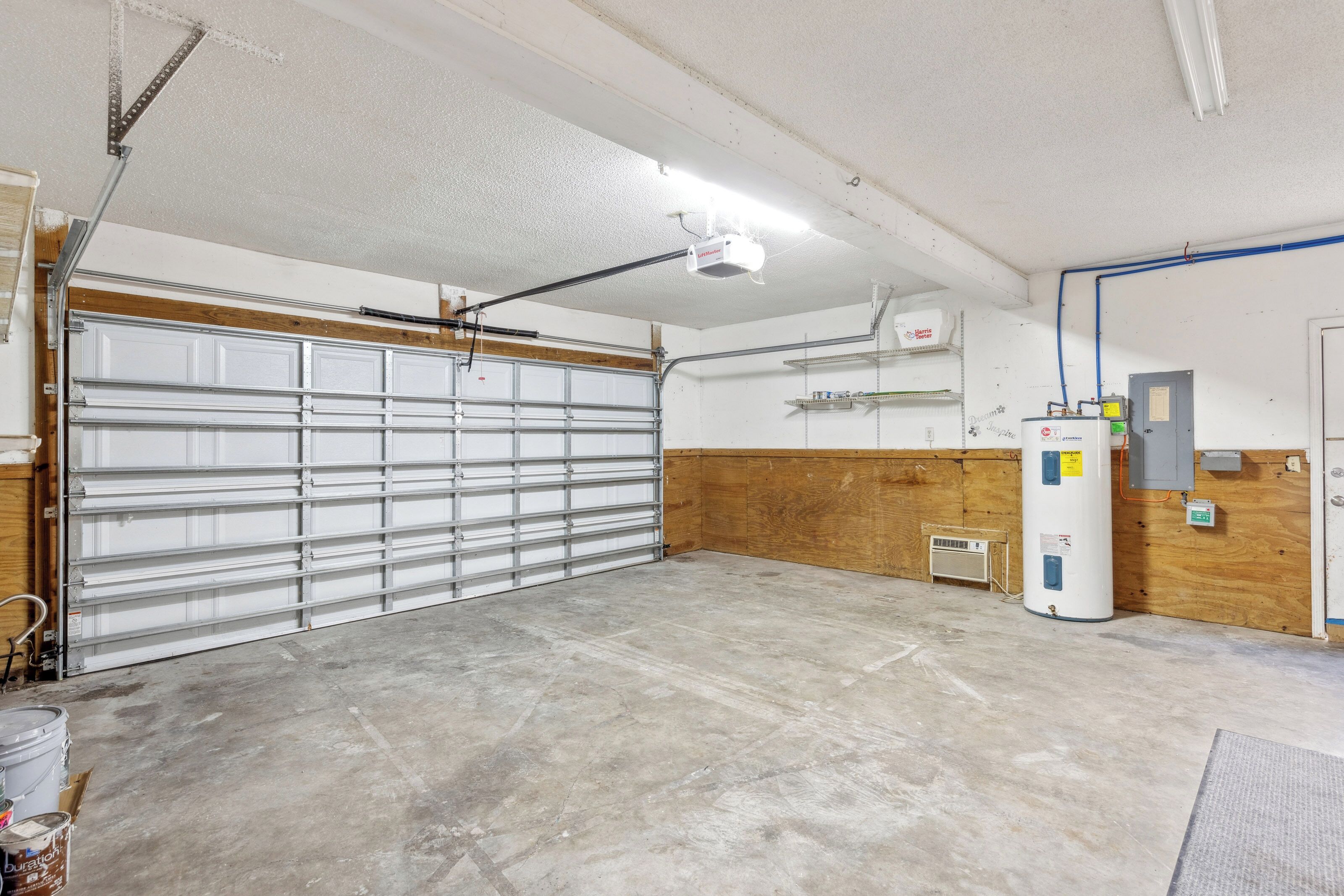 Polished concrete and warm wood wainscoting define this versatile, bright utility space. Ample room and steady overhead glow create a practical, clean environment for your gear or car during your stay.