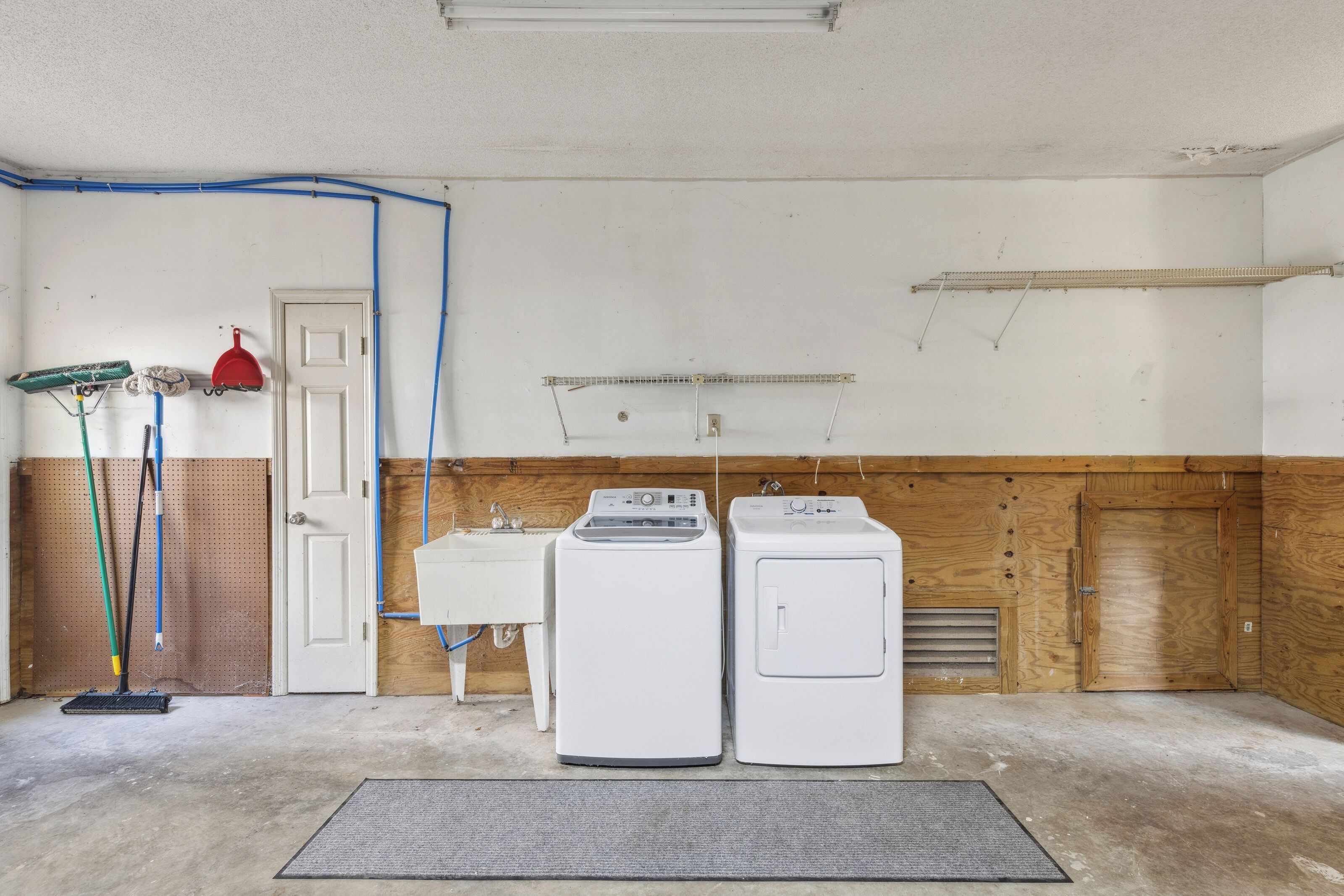 Natural wood paneling lines this functional utility space, providing a rustic touch to the convenient on-site laundry area. Bright white appliances and a deep wash basin ensure you have everything needed for a seamless, stress-free stay.