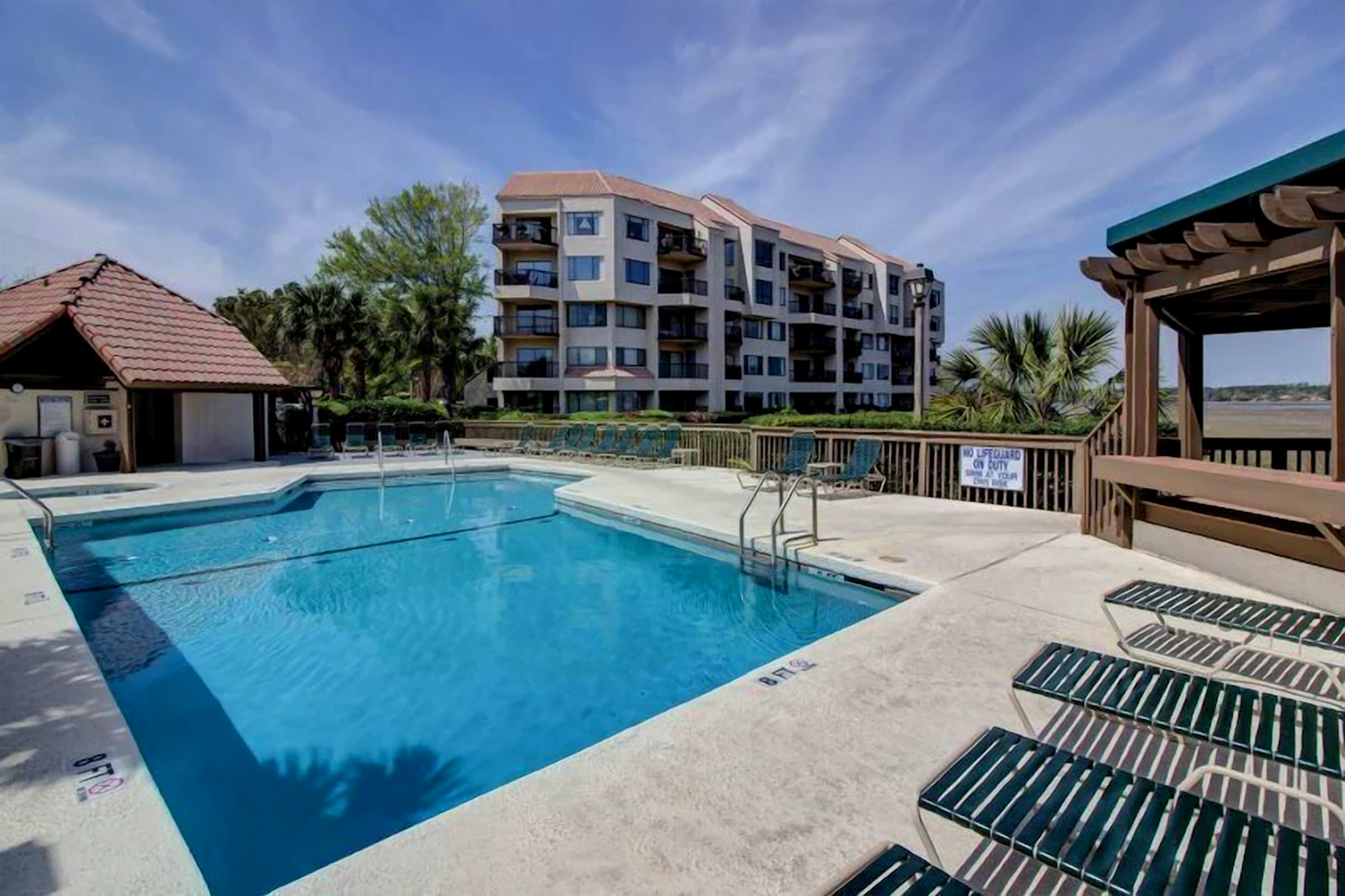 Cerulean water shimmers under a vast sky, inviting you to spend a quiet morning by the pool. Smooth concrete and dark lounge chairs offer a clean, airy space to soak up the coastal breeze and soft midday glow.