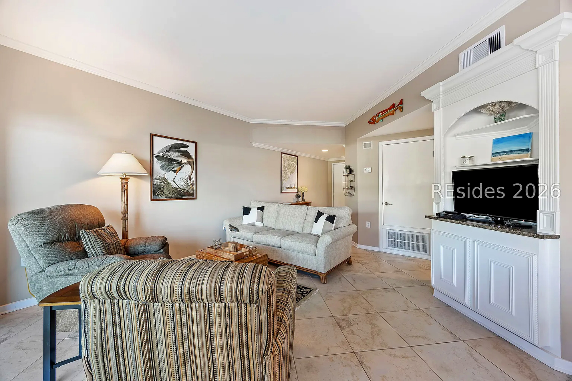 Striped upholstery and soft neutrals create a cozy corner for quiet afternoons. Clean lines meet coastal accents in this airy living space, where smooth tile floors and a classic built-in offer a timeless setting for your next movie night.